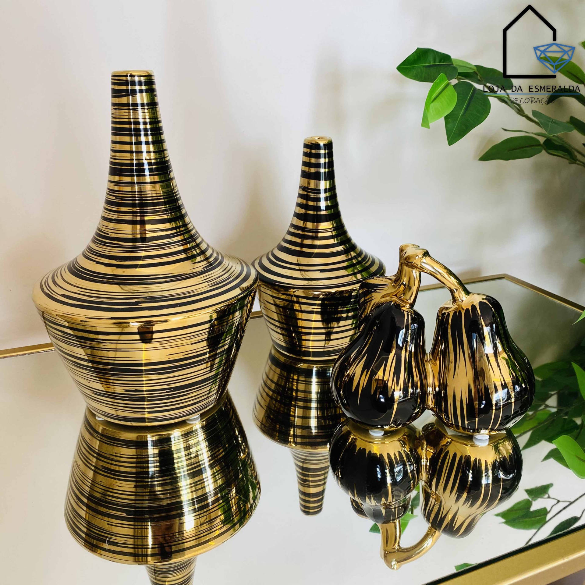Objetos decorativos dourados com padrões pretos sobre mesa espelhada