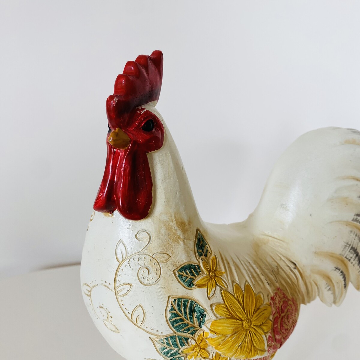 Figura decorativa de galo branco com detalhes vermelhos e flores pintadas.