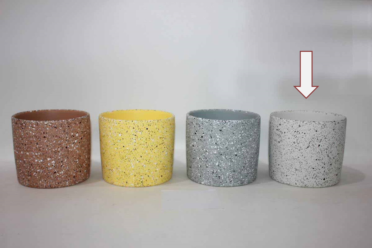 Quatro vasos cilíndricos coloridos com textura pontilhada em superfície branca
