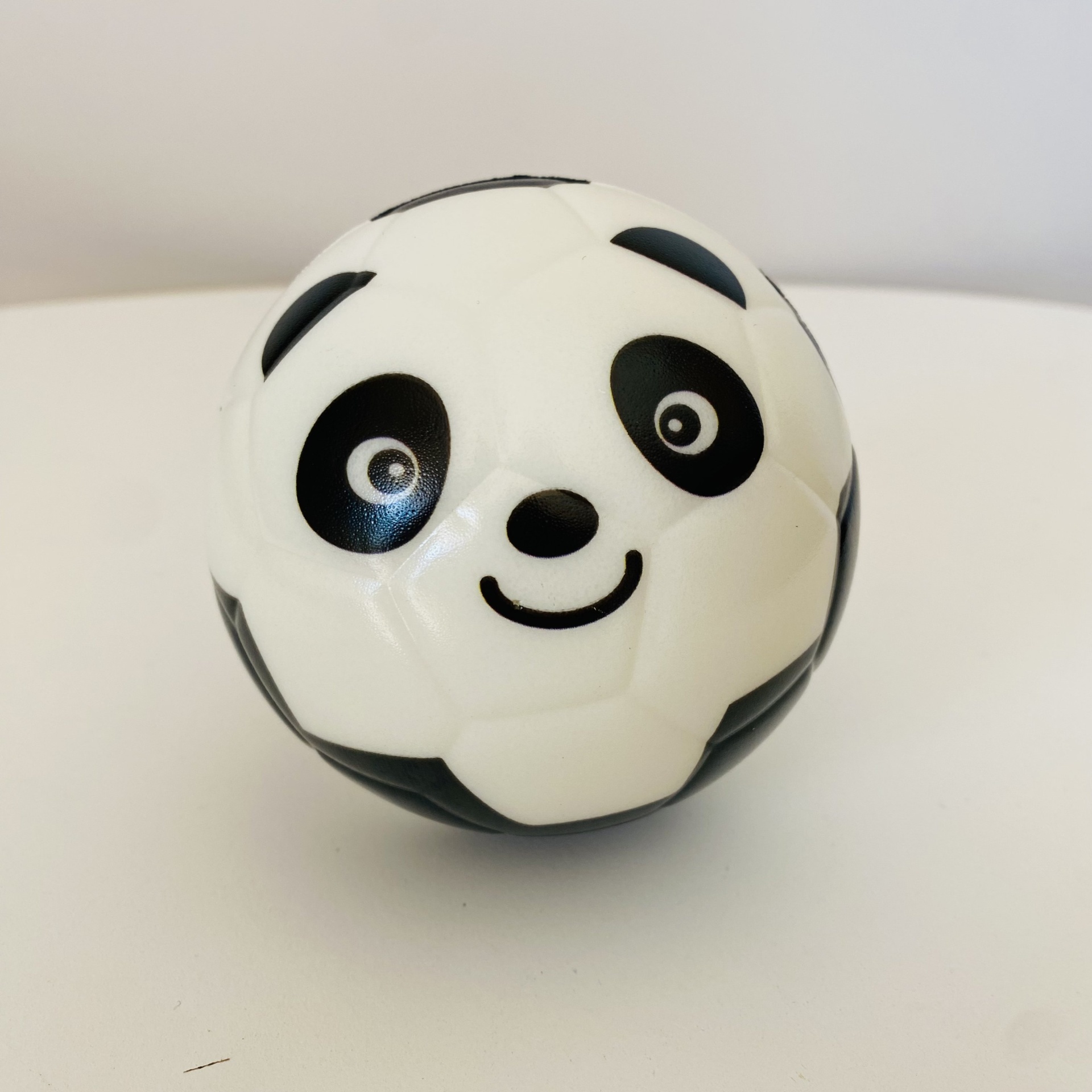 Bola branca e preta com rosto de panda sorridente