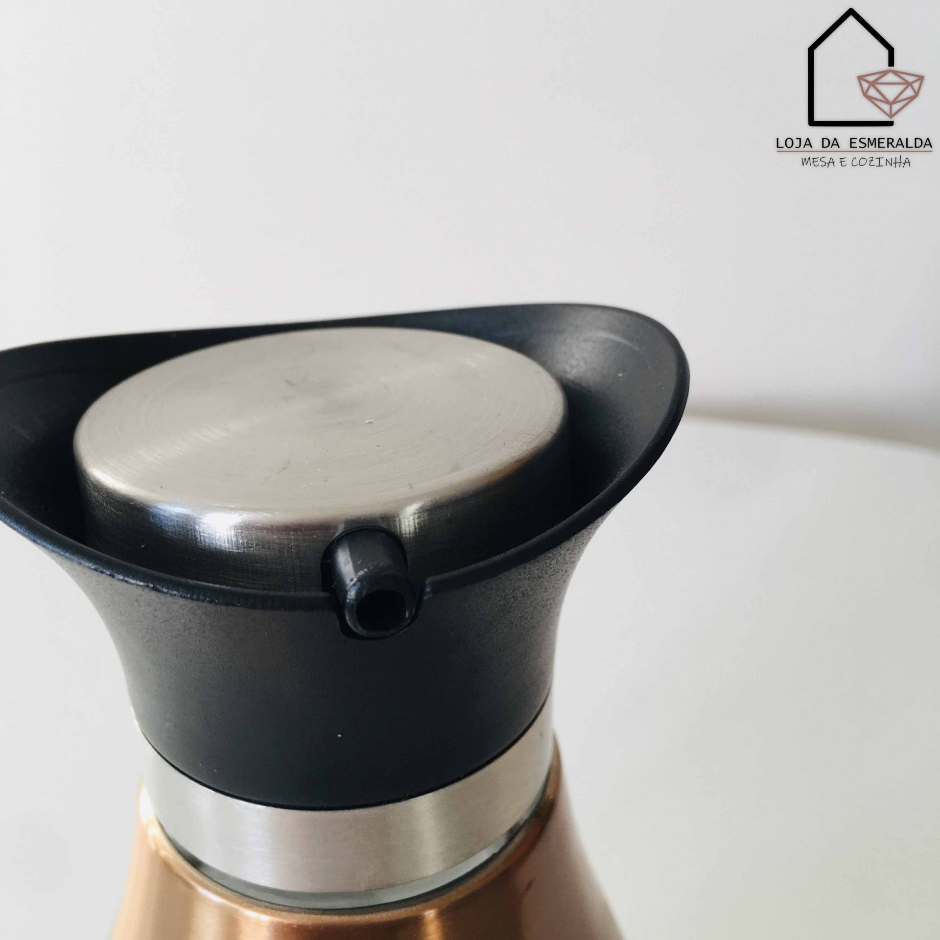 Parte superior de recipiente metálico com bico vertedor preto e corpo dourado, logótipo LOJA DA ESMERALDA no fundo