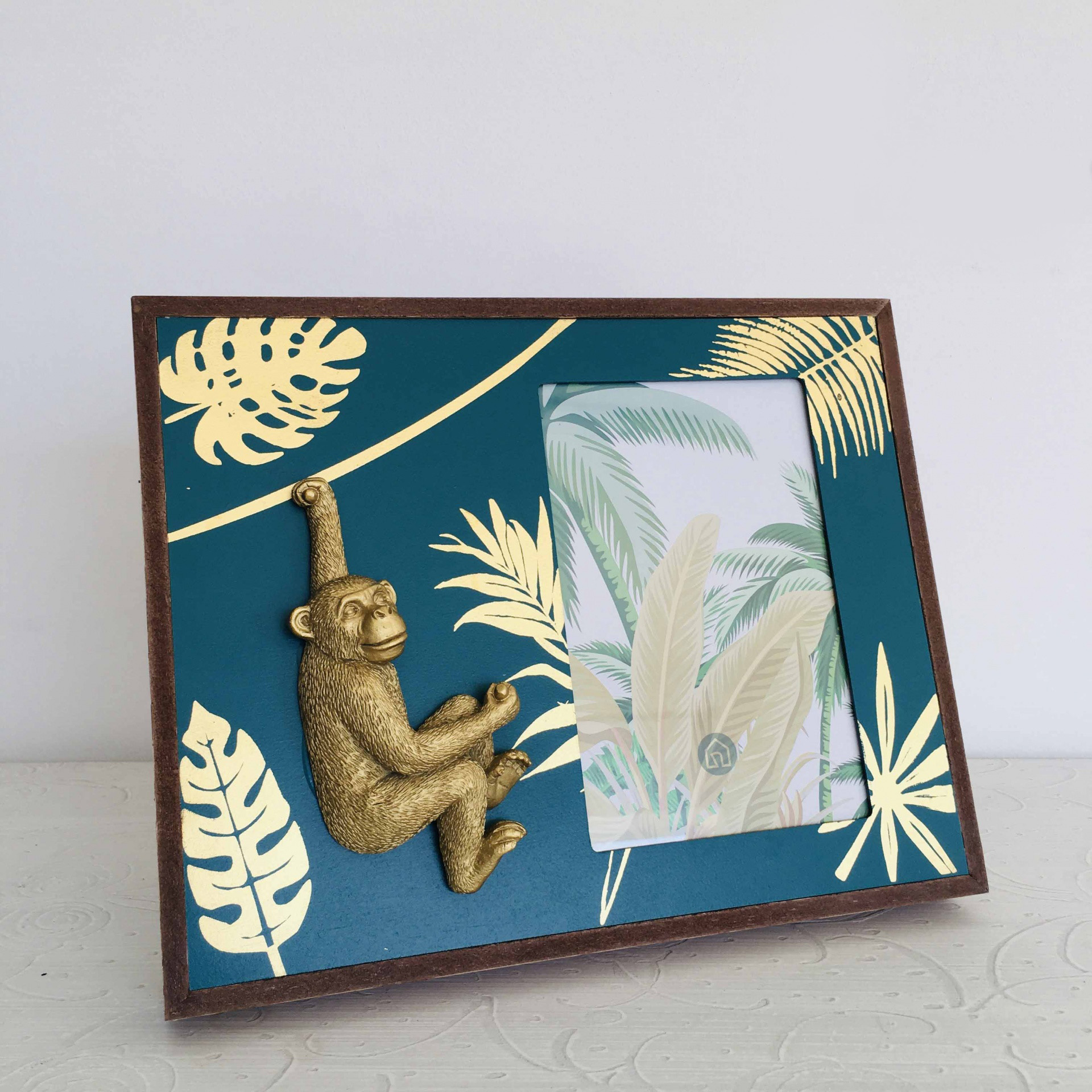 Moldura fotográfica decorativa com macaco dourado e padrão de folhas