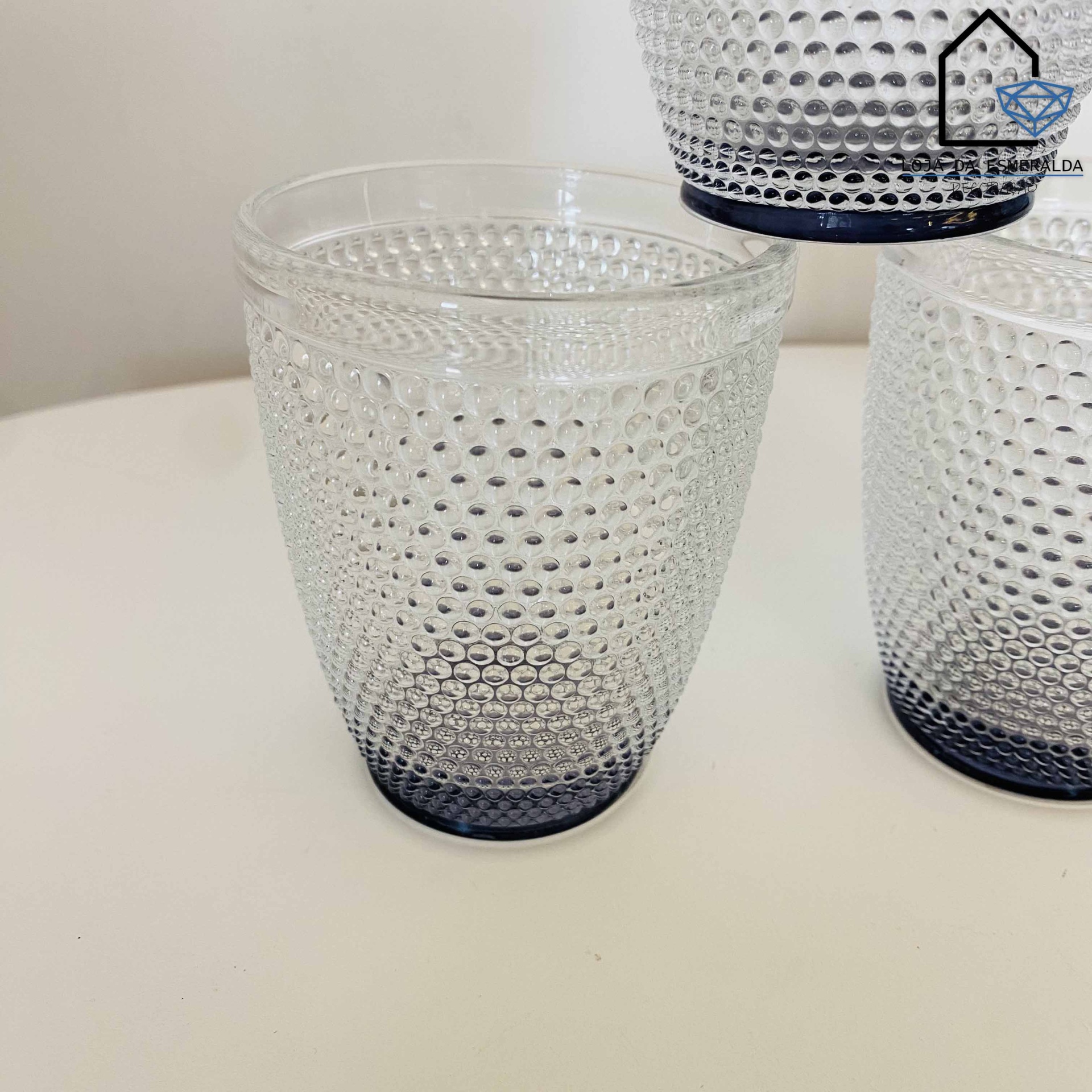 Copo de vidro transparente com padrão de bolhas salientes e base cinza