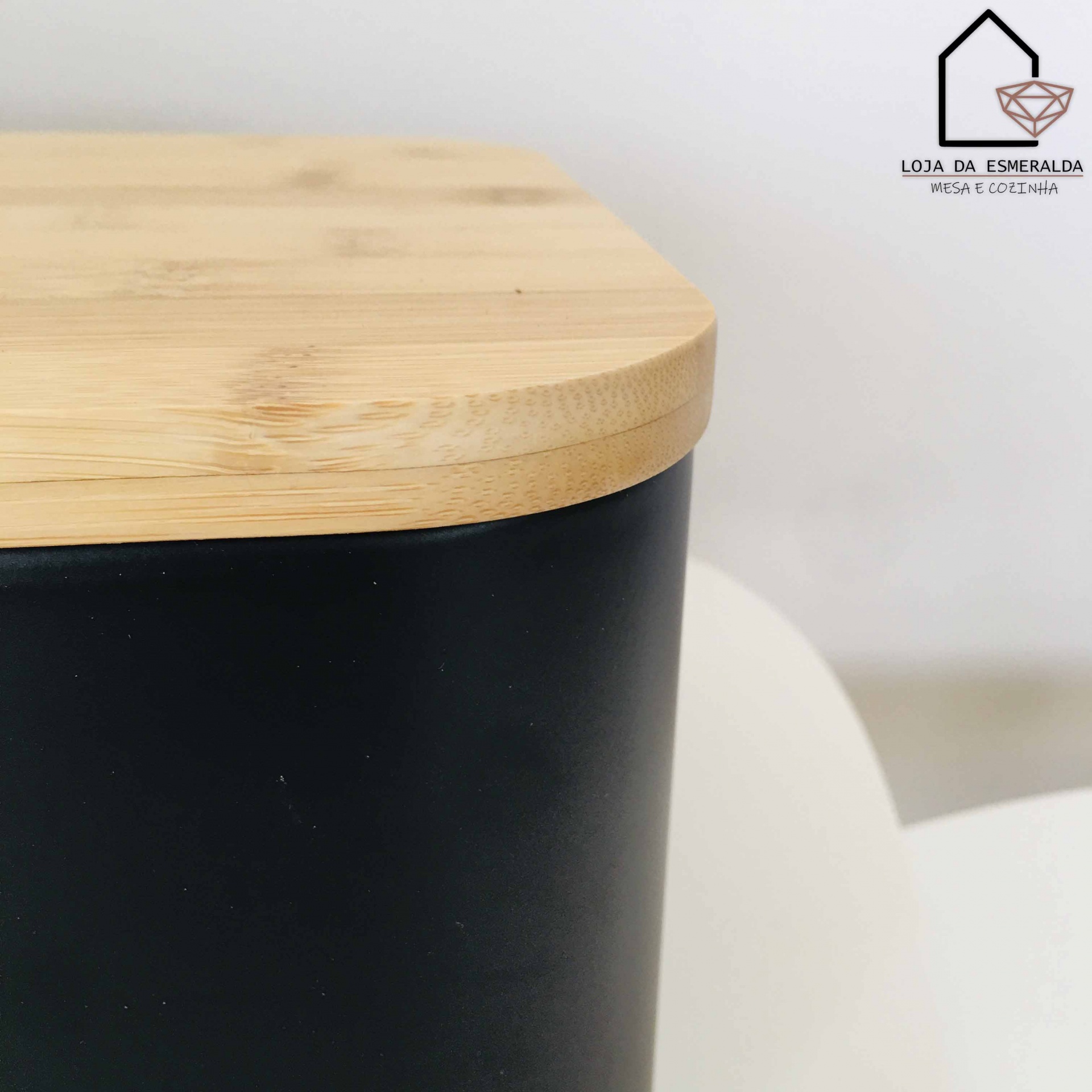Recipiente preto com tampa de madeira clara sobre superfície branca