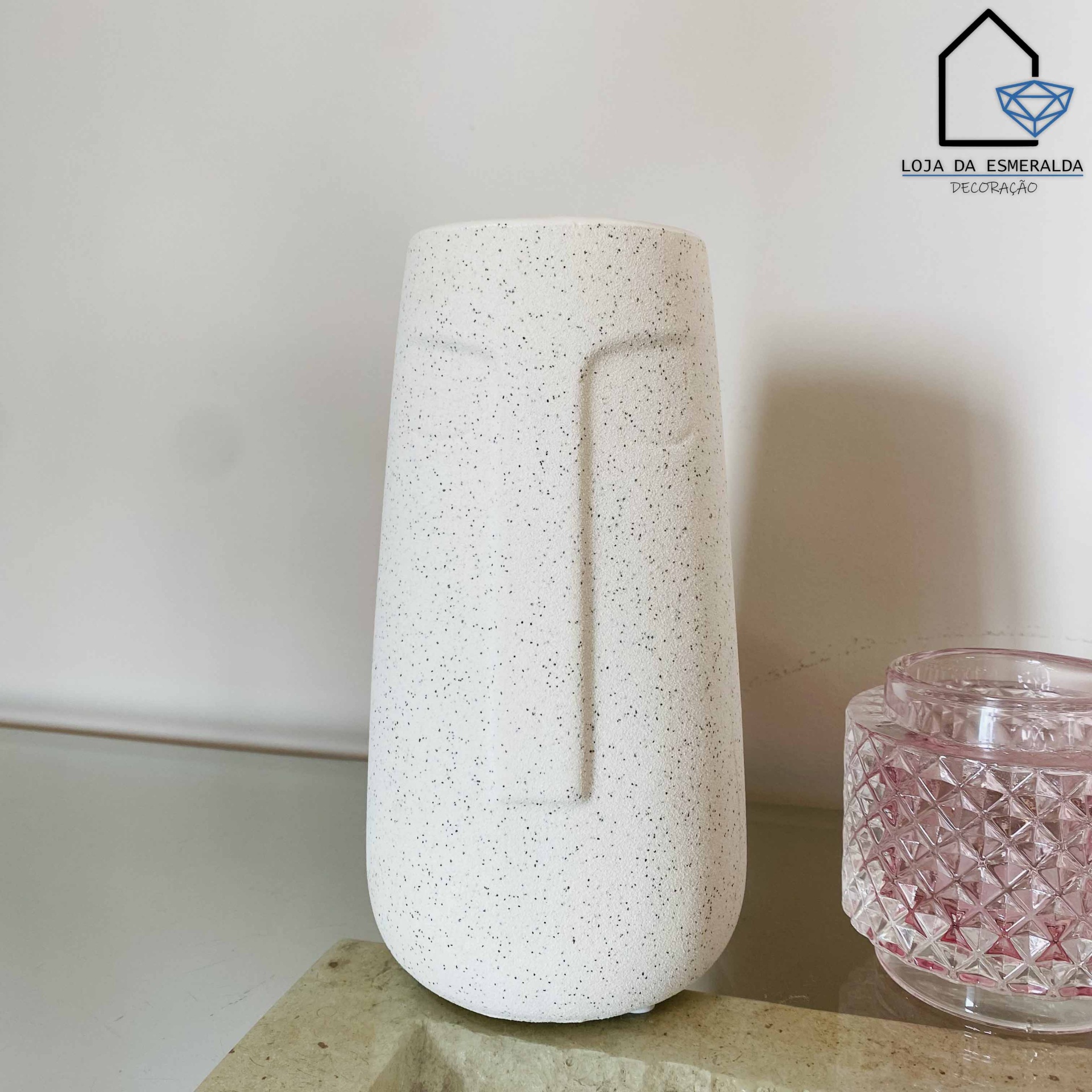 Vaso decorativo branco com textura pontilhada perto de recipiente de vidro