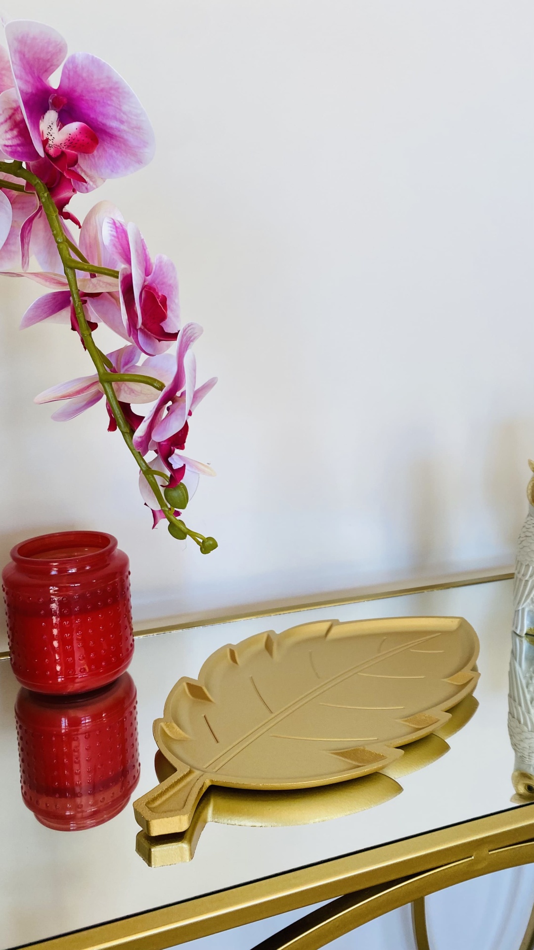 Bandeja dourada em forma de folha com vaso vermelho e orquídea lilás