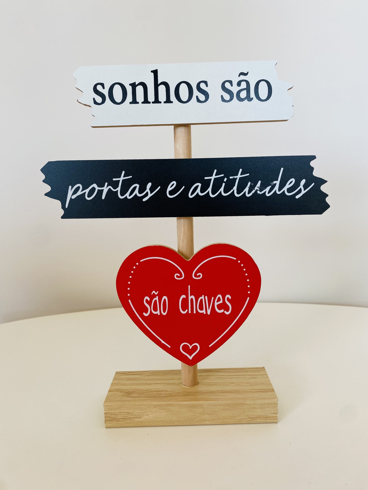 Objeto decorativo em madeira com textos em português, incluindo um coração vermelho
