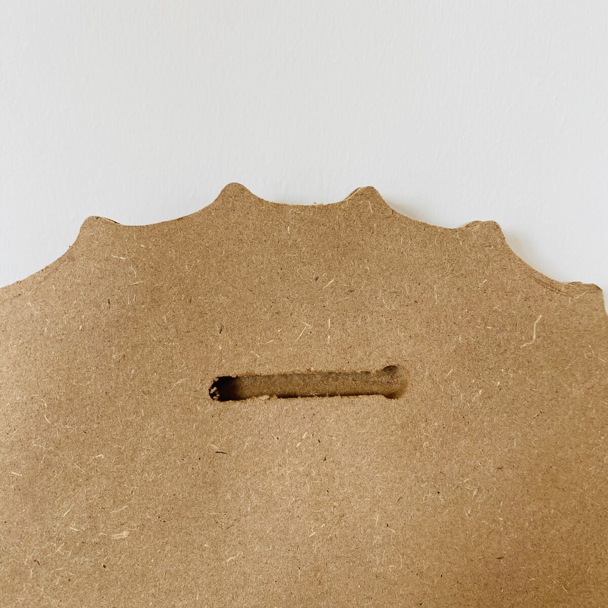 Peça de madeira MDF castanha com recorte ondulado e ranhura horizontal