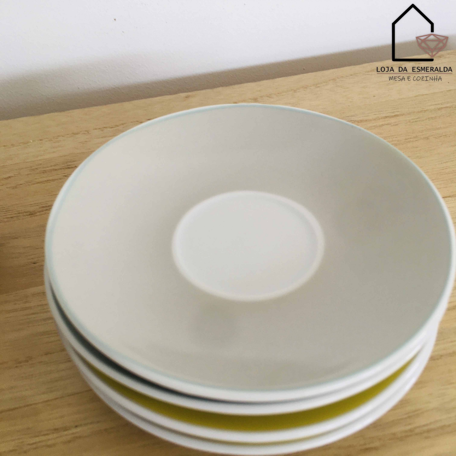 Quatro pratos cerâmicos empilhados com logótipo Loja da Esmeralda ao fundo