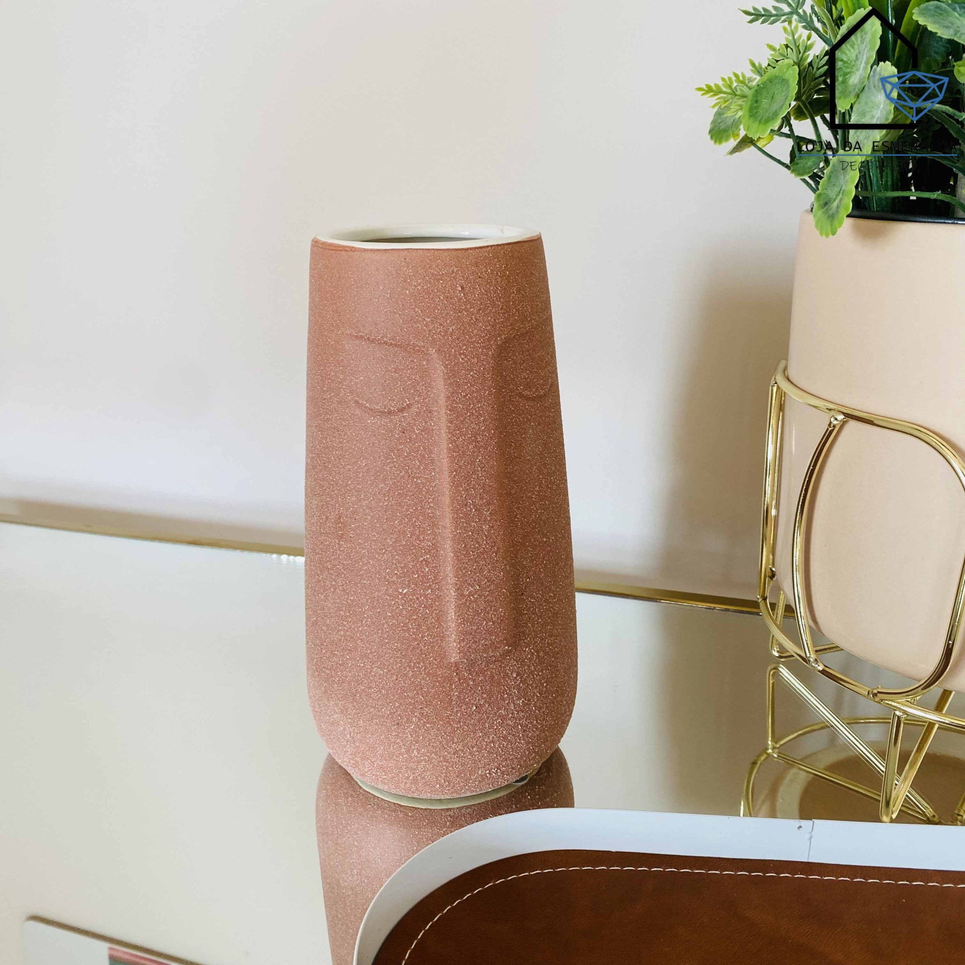 Vaso decorativo em forma de rosto rosa em cima de superfície espelhada