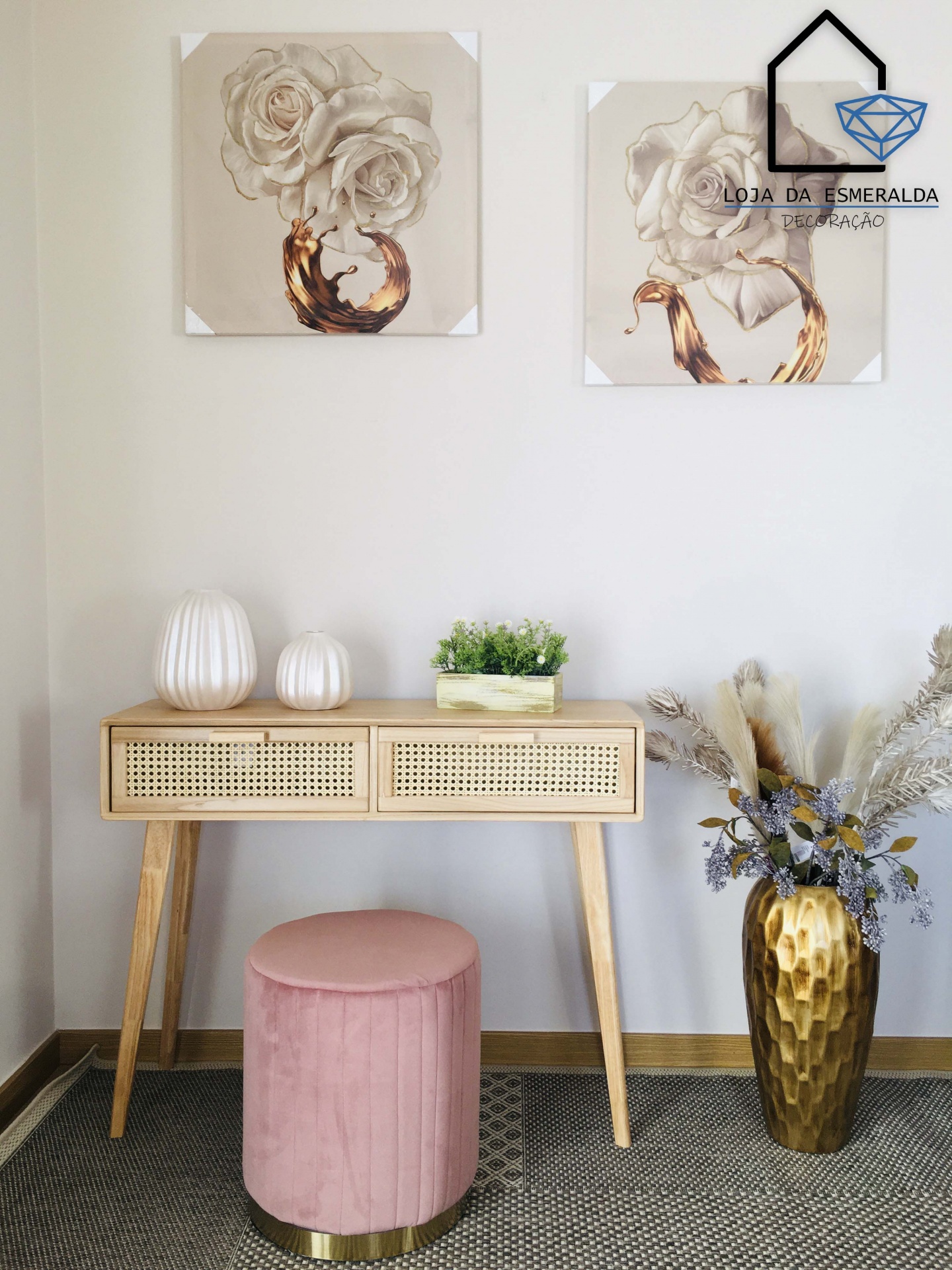 Consola de madeira com cestos de vime, banco rosa, quadros com flores brancas e vaso dourado com flores secas