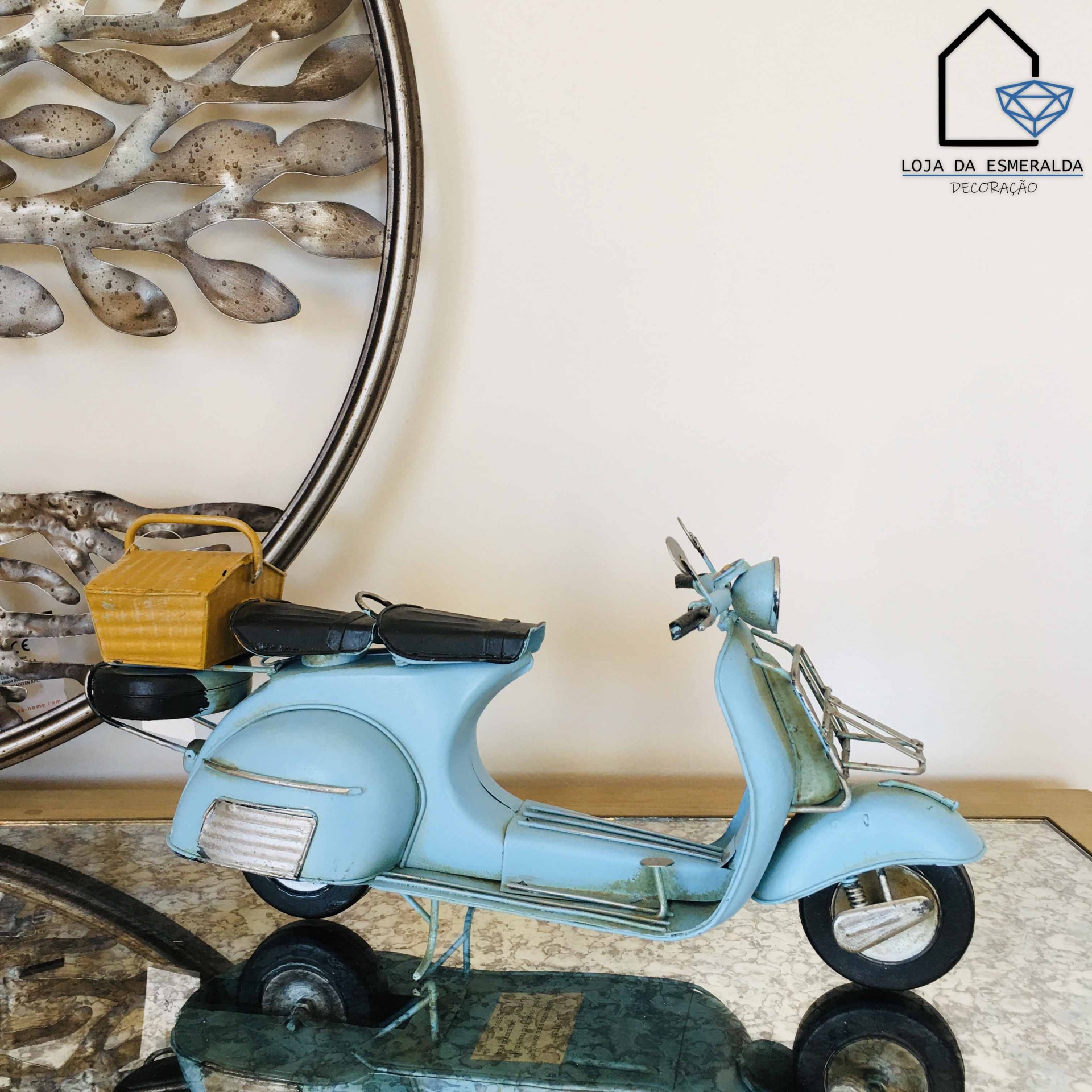 Miniatura de mota azul claro em metal com capacete amarelo em mesa de vidro