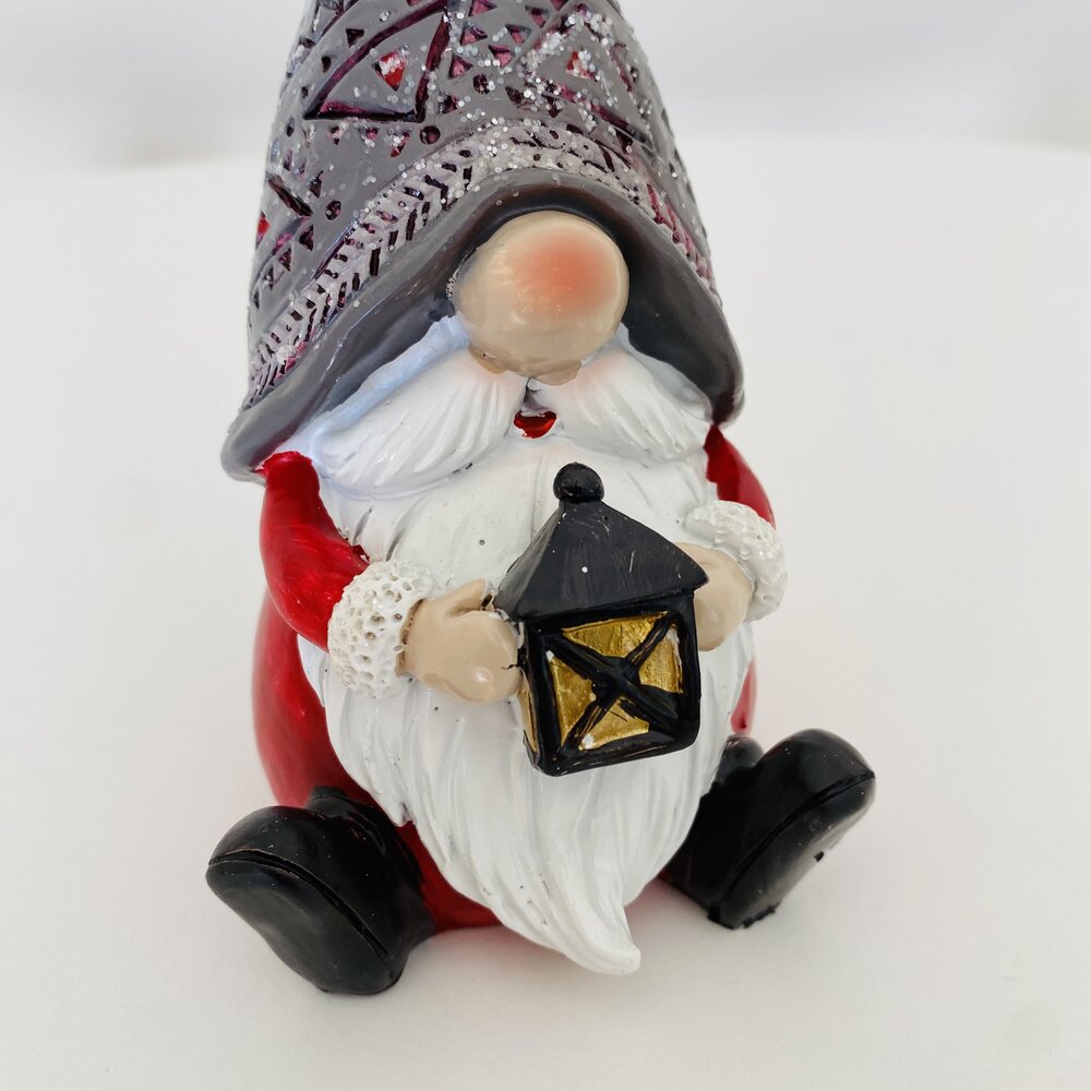 Gnomo decorativo sentado com chapéu cinza e lanterna