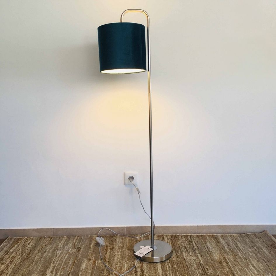 Candeeiro de pé prateado com cúpula de veludo azul escuro contra parede branca