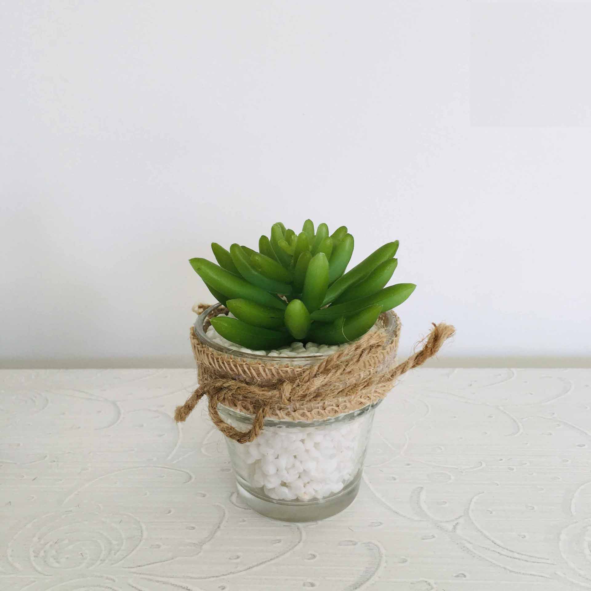 Vaso de vidro com planta suculenta artificial e pedras brancas