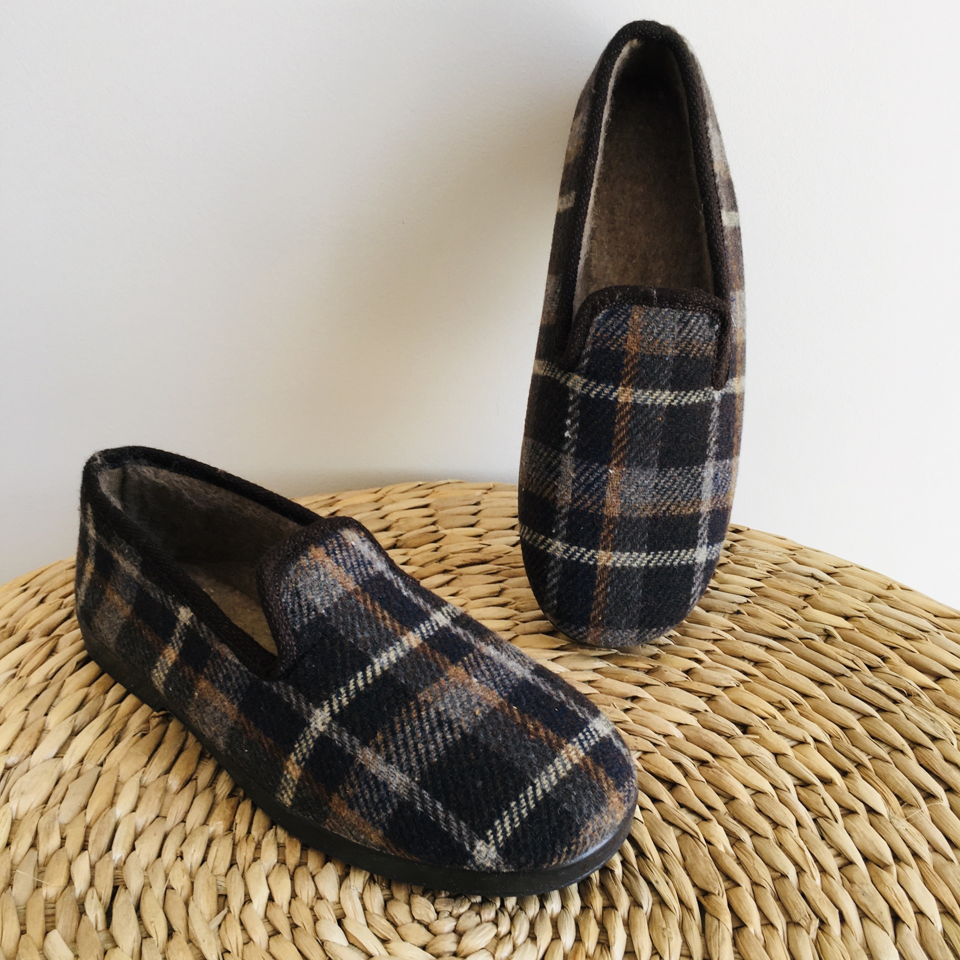 Sapatos mocassim com padrão xadrez castanho e cinza sobre superfície trançada