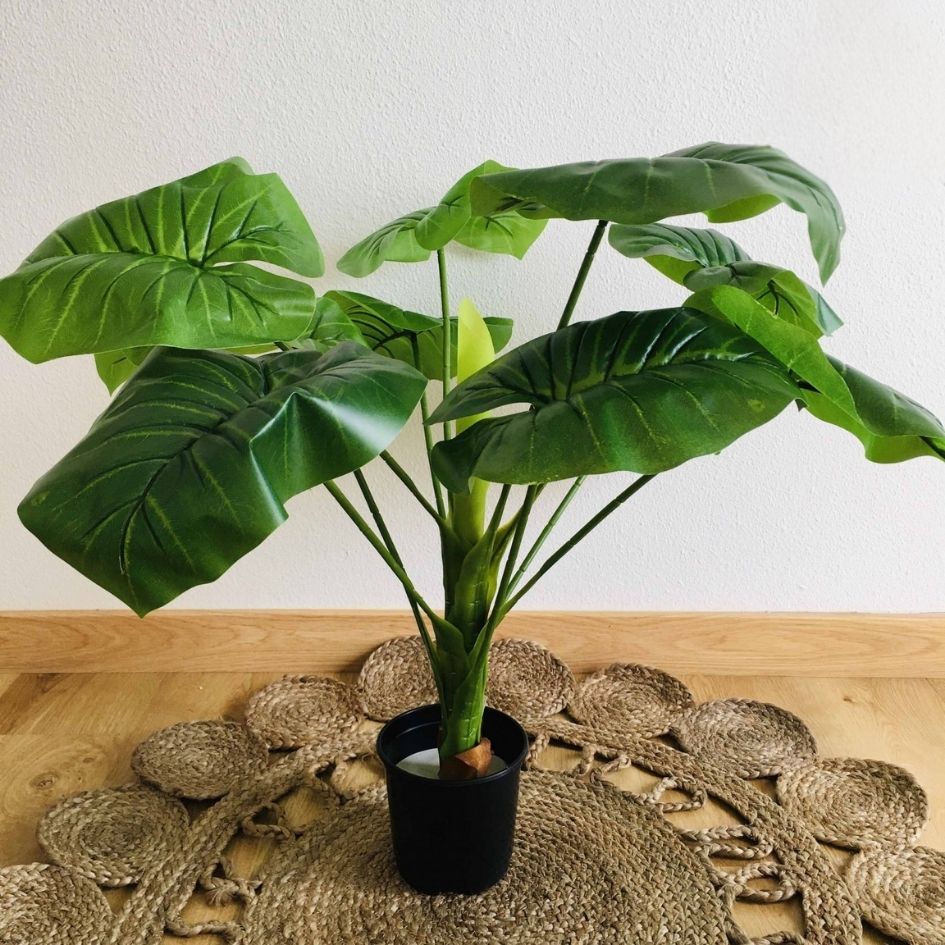 Planta artificial em vaso preto sobre tapete de fibras naturais