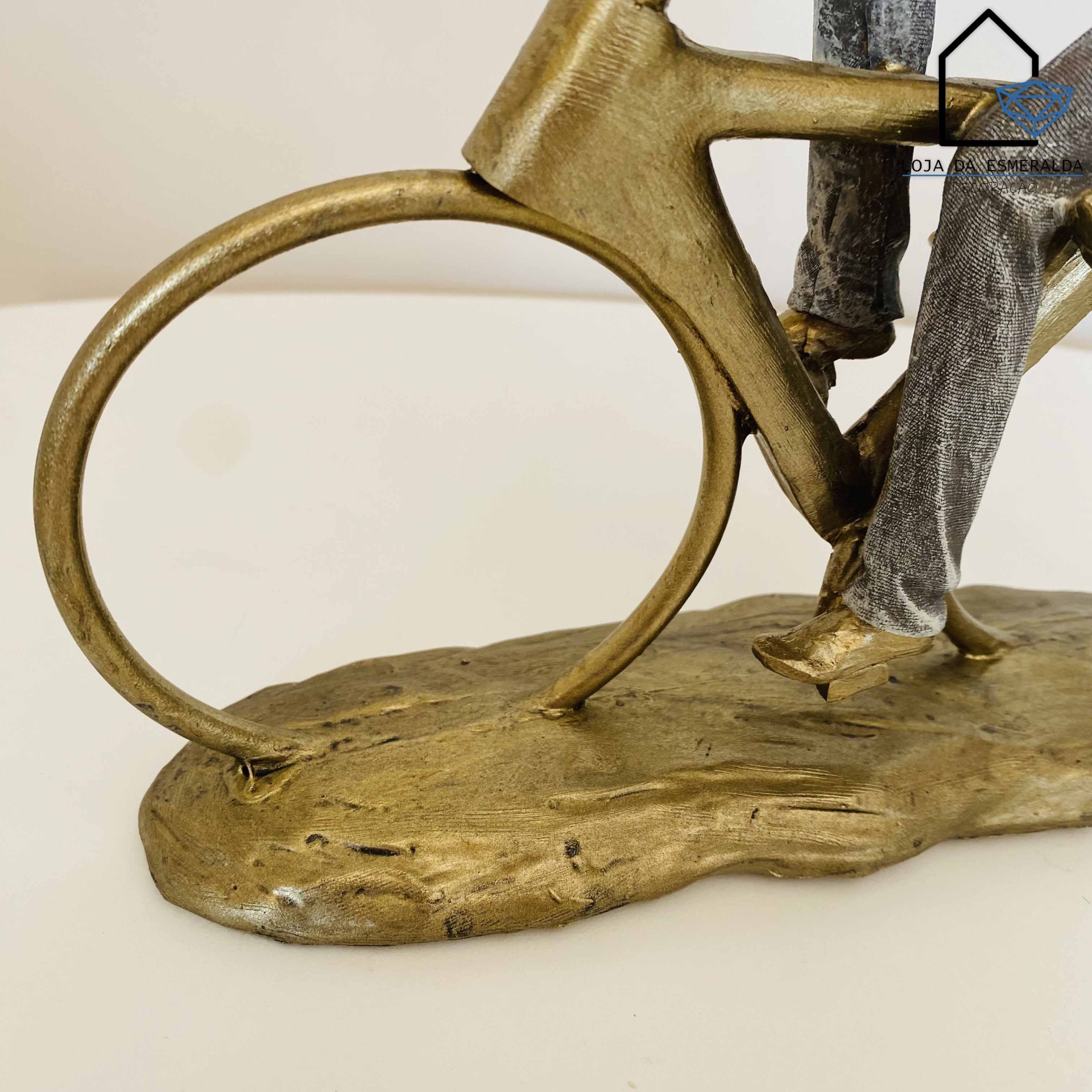 Estátua decorativa de figura numa bicicleta dourada com base irregular