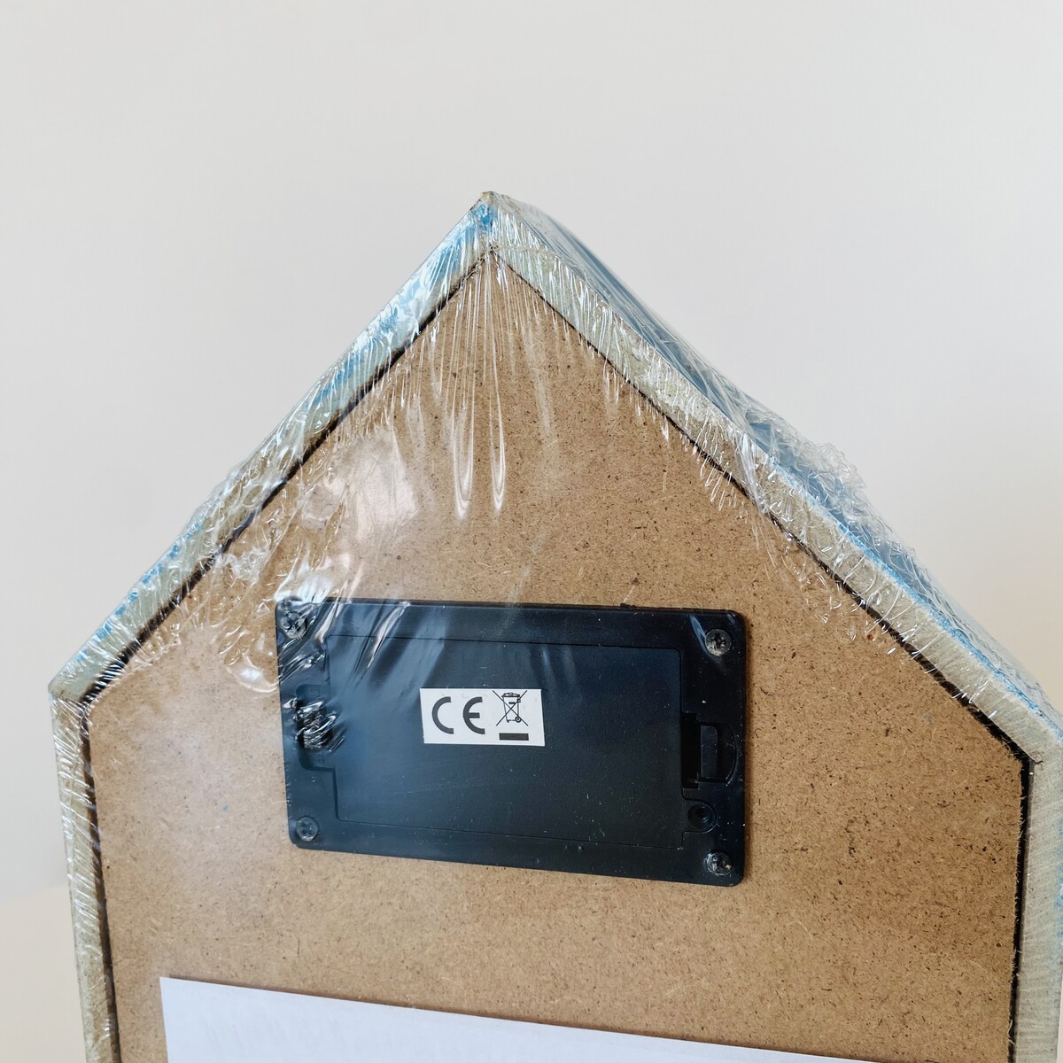 Parte traseira de objeto em forma de casa com tampa de bateria preta e plástico transparente