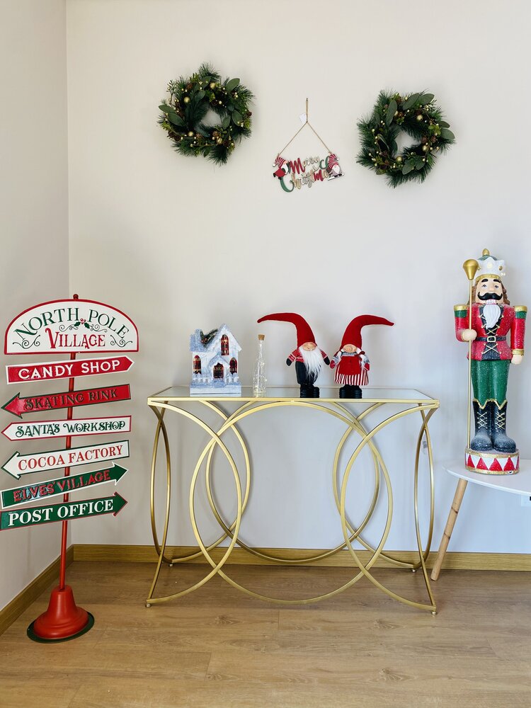 Decoração de Natal com coroas verdes, placa colorida do Pólo Norte, figuras com gorro vermelho, casinha branca e soldado quebra-nozes.