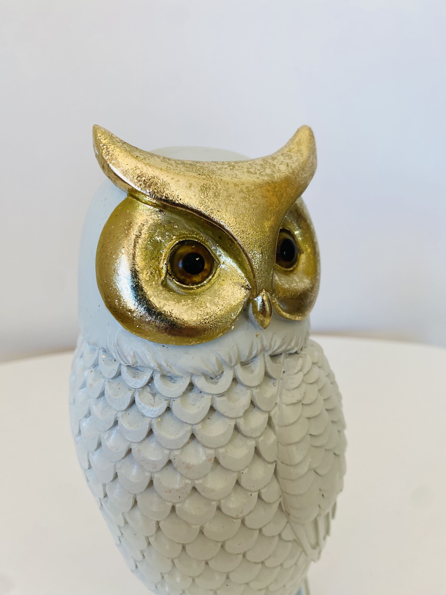 Figura decorativa de coruja branca com detalhes dourados e olhos castanhos