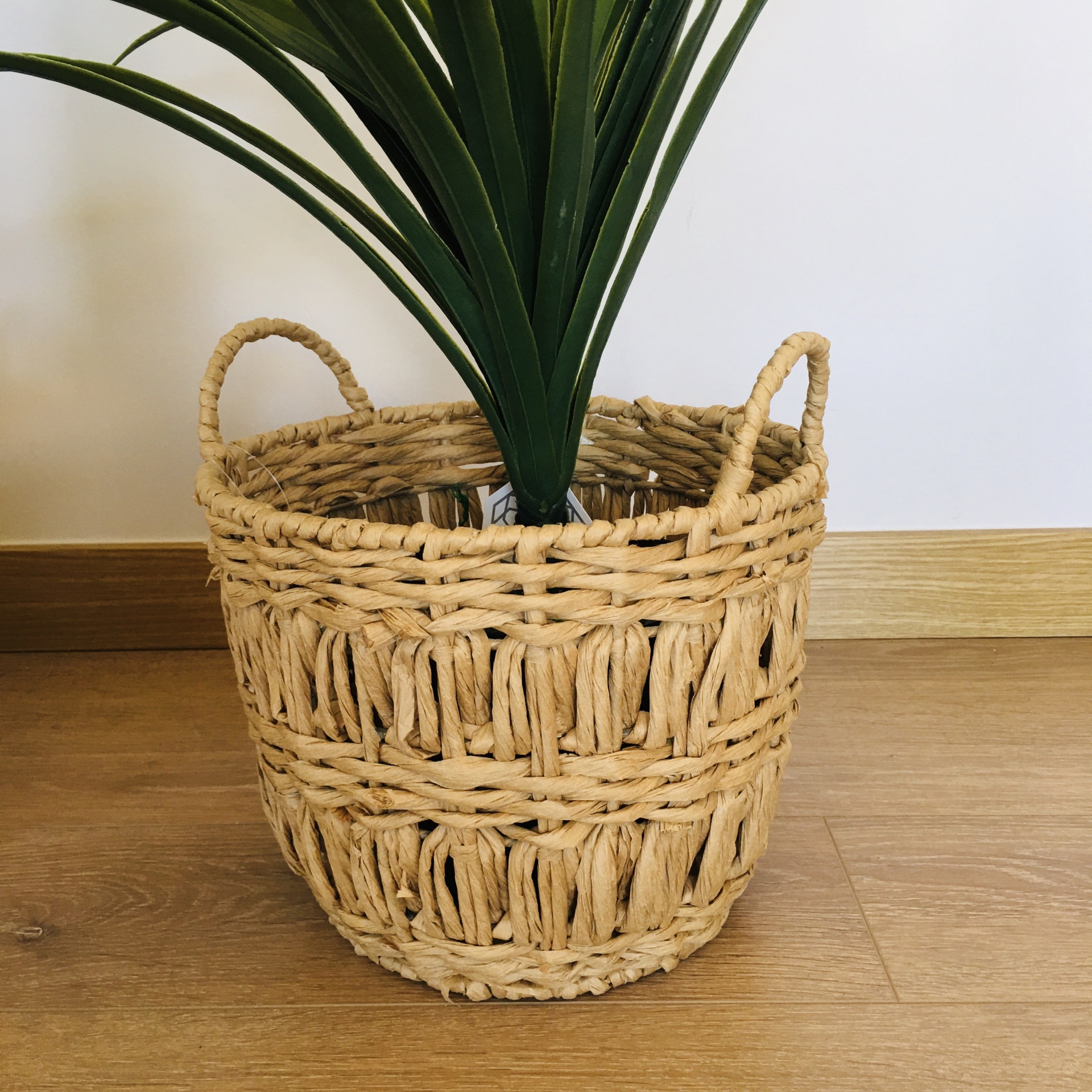 Cesto decorativo trançado de palha com planta verde e duas alças