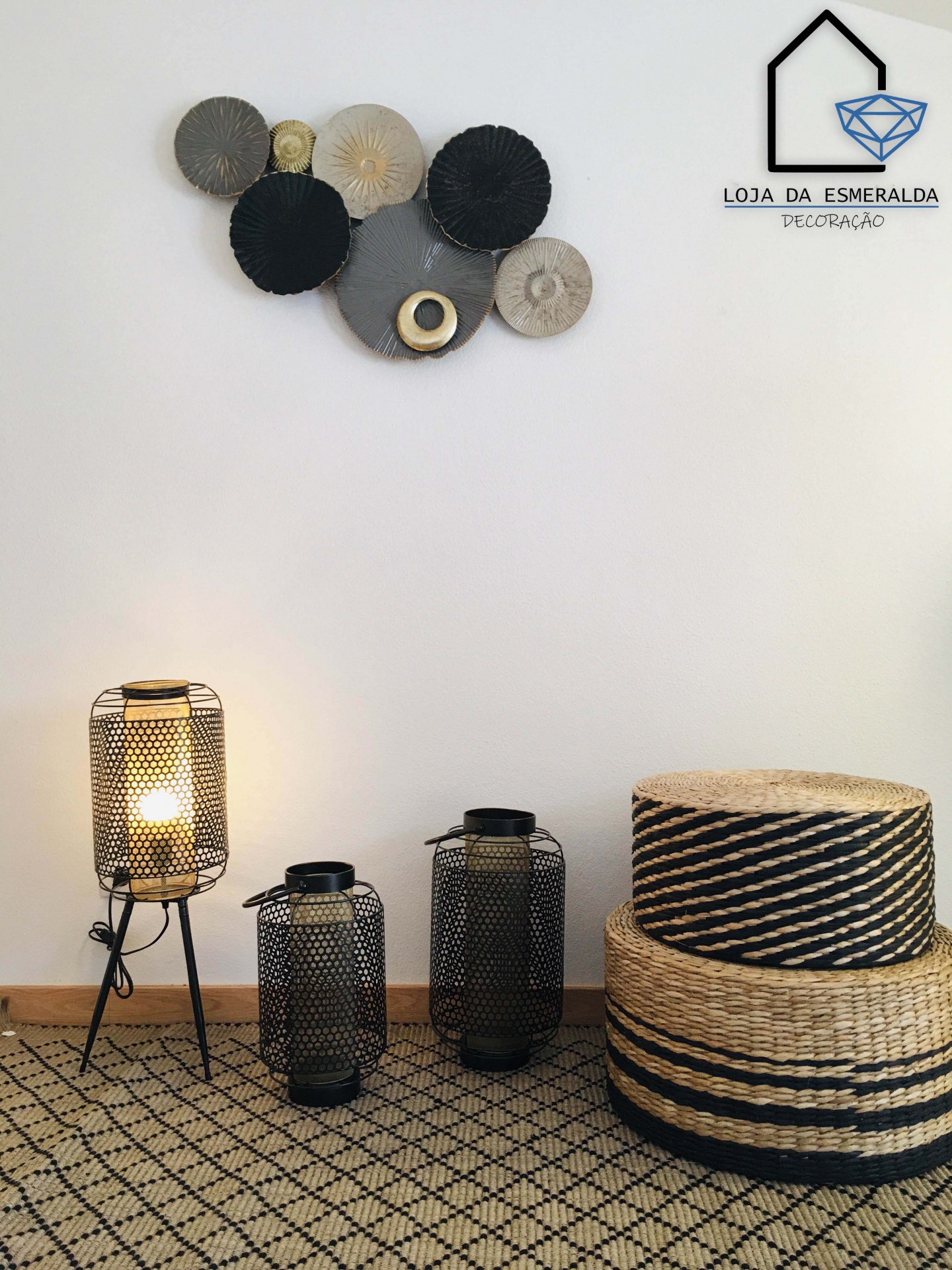 Decoração interior com lanternas de metal, cestos de palha, tapete geométrico e arte na parede em tom neutro