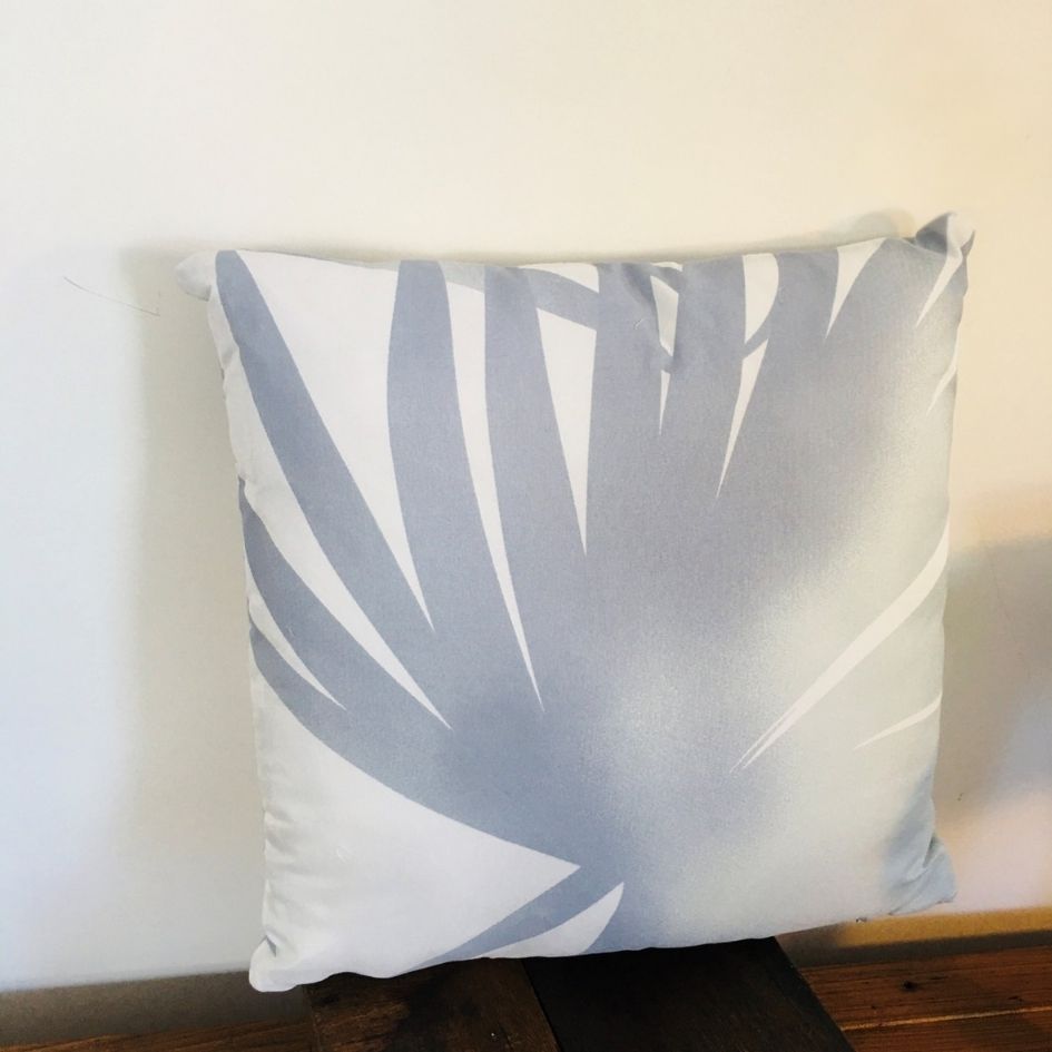 Almofada quadrada cinzenta e branca com padrão abstrato em fundo branco