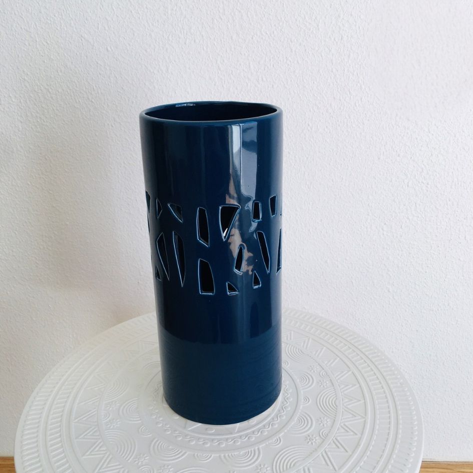 Vaso azul escuro com recortes sobre mesa branca decorativa