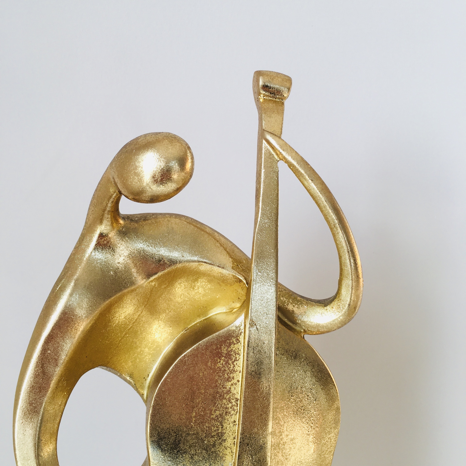 Escultura decorativa abstrata em metal dourado com figura e violoncelo