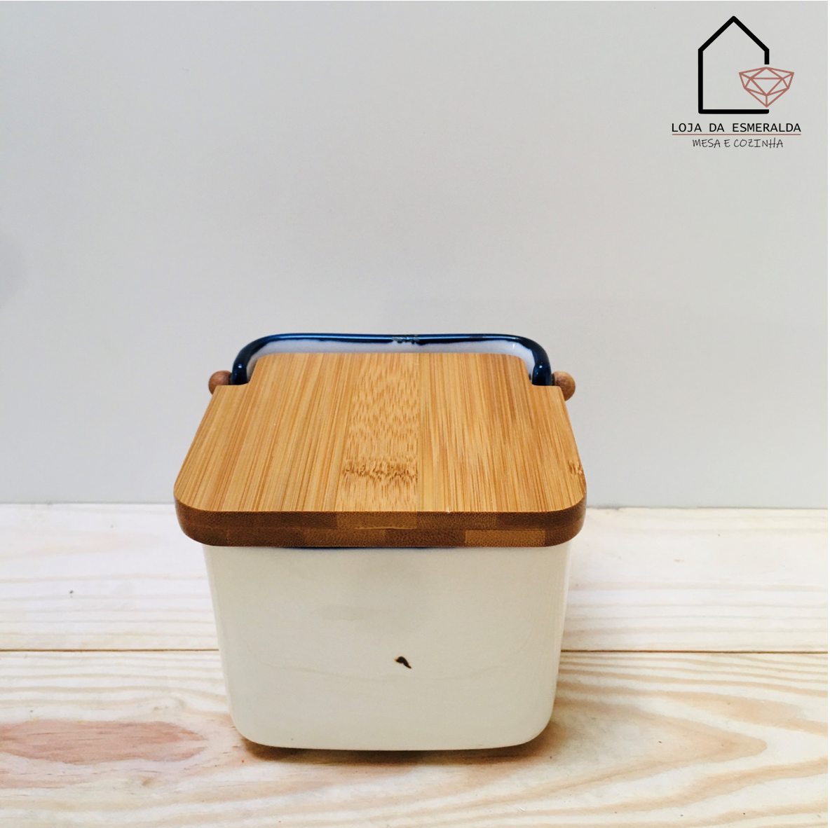 Recipiente cerâmico branco com tampa de madeira e pega preta sobre superfície de madeira clara