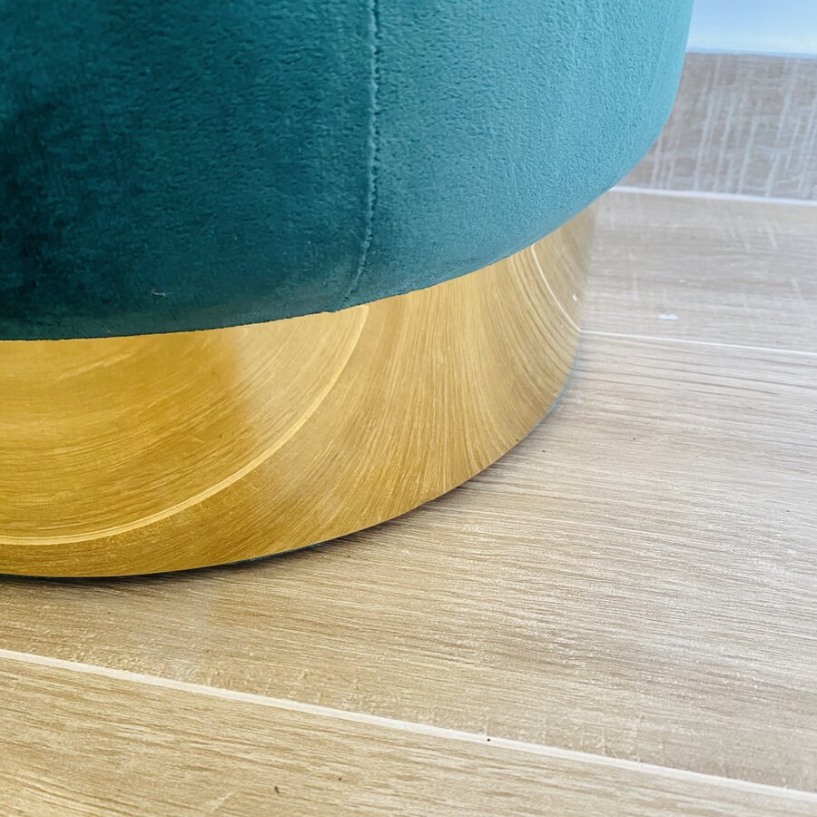 Base dourada de móvel estofado em tecido verde sobre chão claro