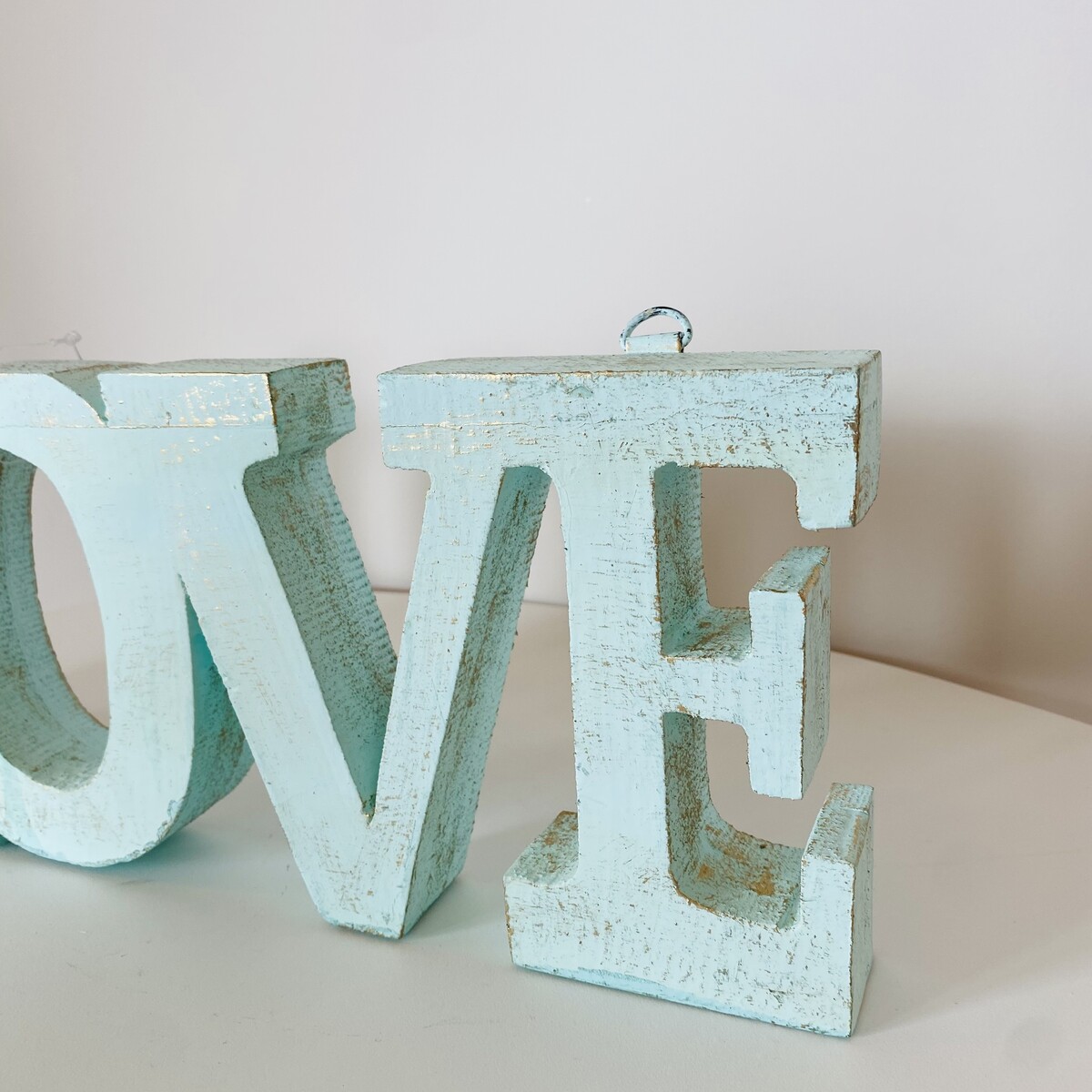 Letra decorativa em madeira azul claro envelhecida formando a palavra LOVE