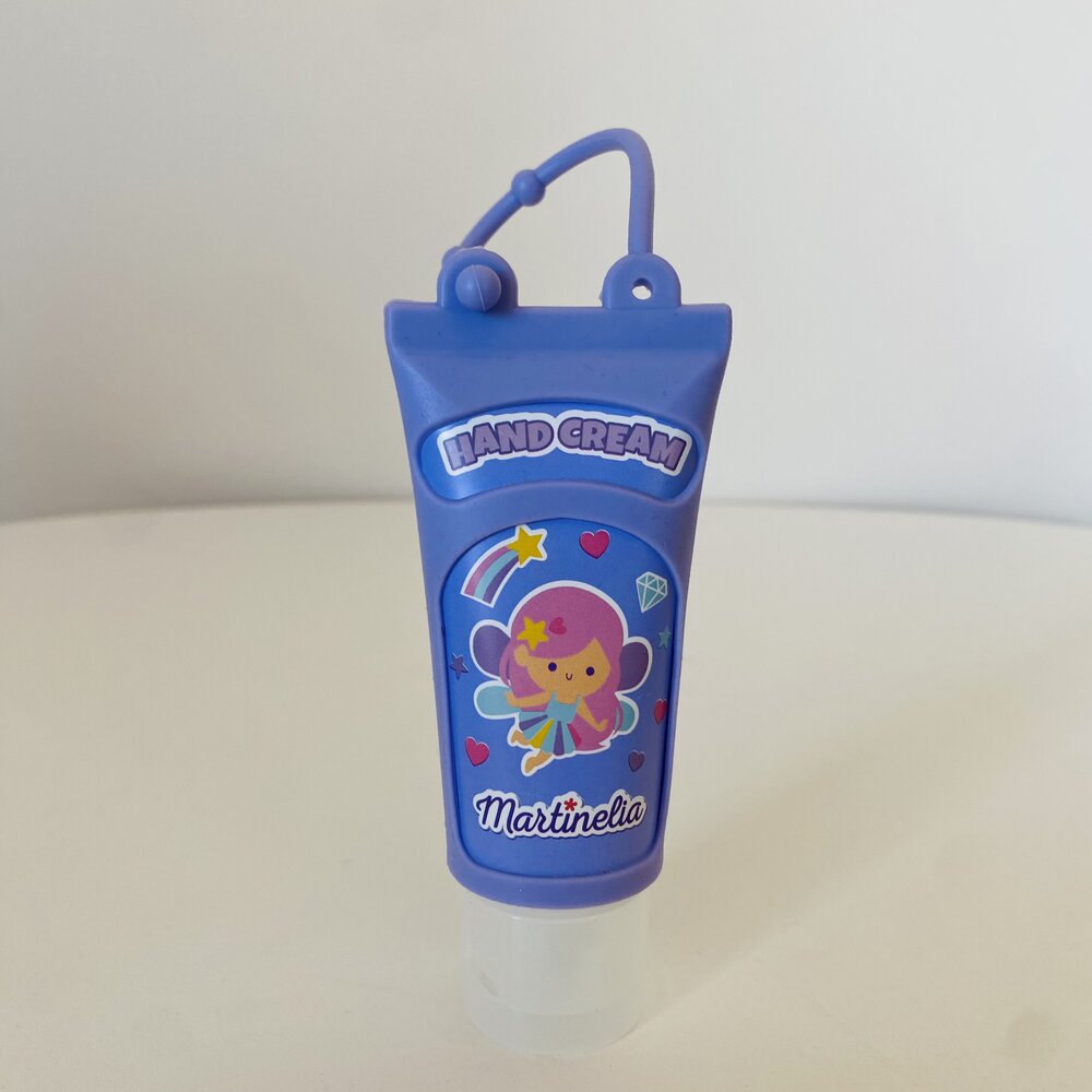 Frasco azul pequeno em formato de creme com ilustração de personagem e texto 'HAND CREAM' e 'Martineli's'