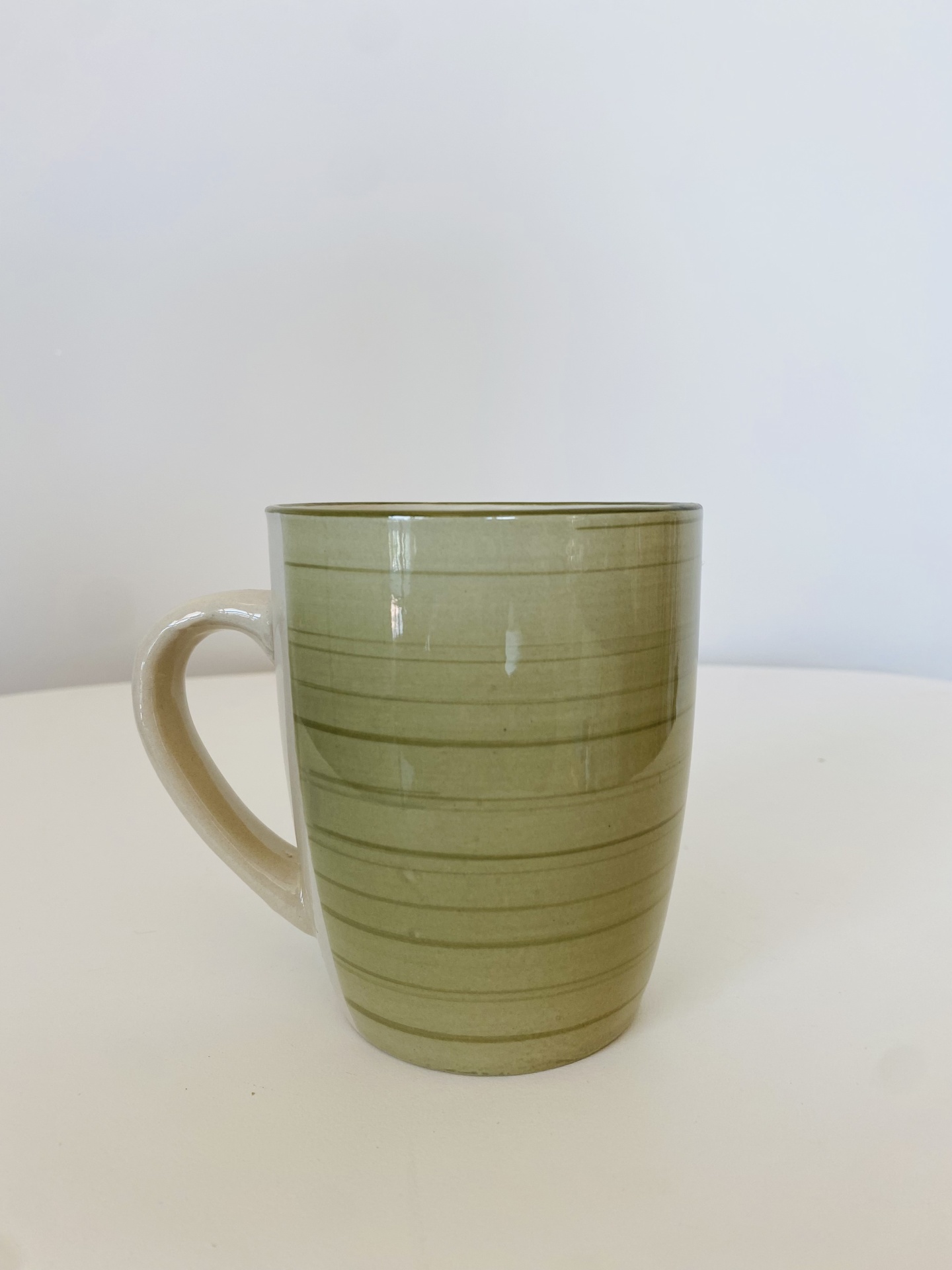 Caneca de cerâmica verde com riscas horizontais e asa creme