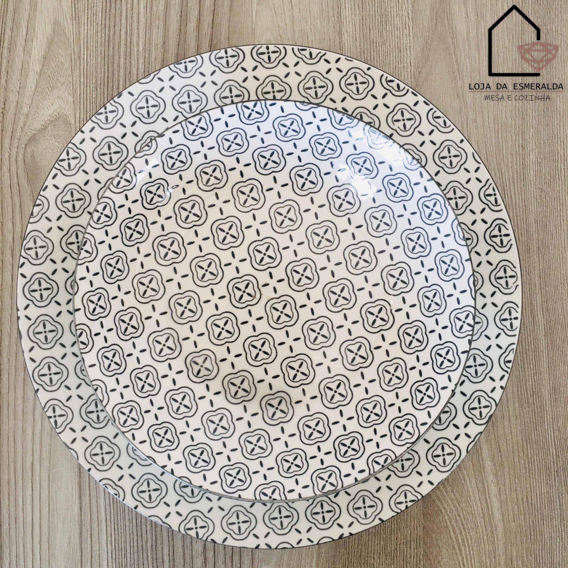 Prato de cerâmica branco com padrão geométrico preto sobre madeira clara