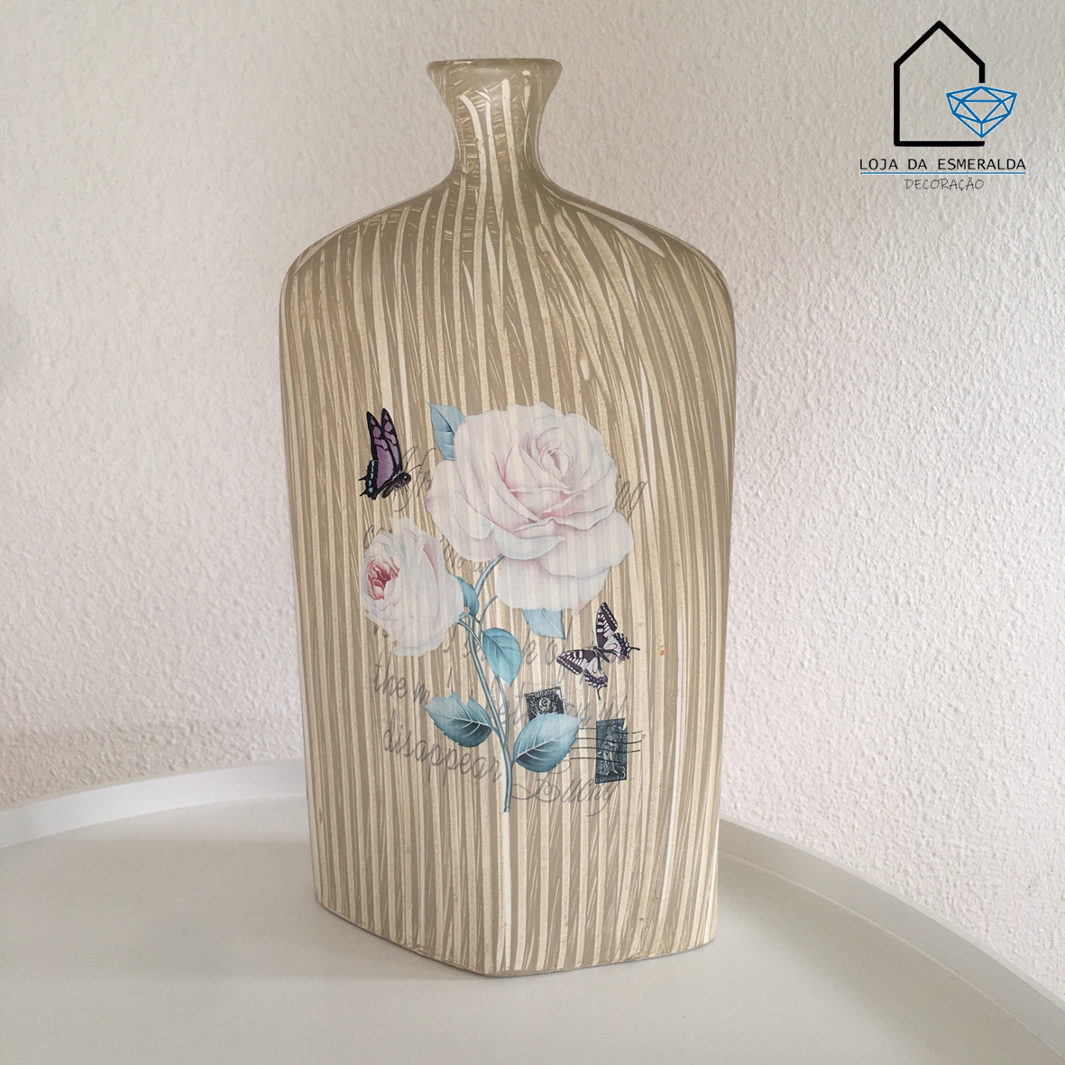 Vaso decorativo em cerâmica bege com flores rosas e borboletas sobre superfície branca