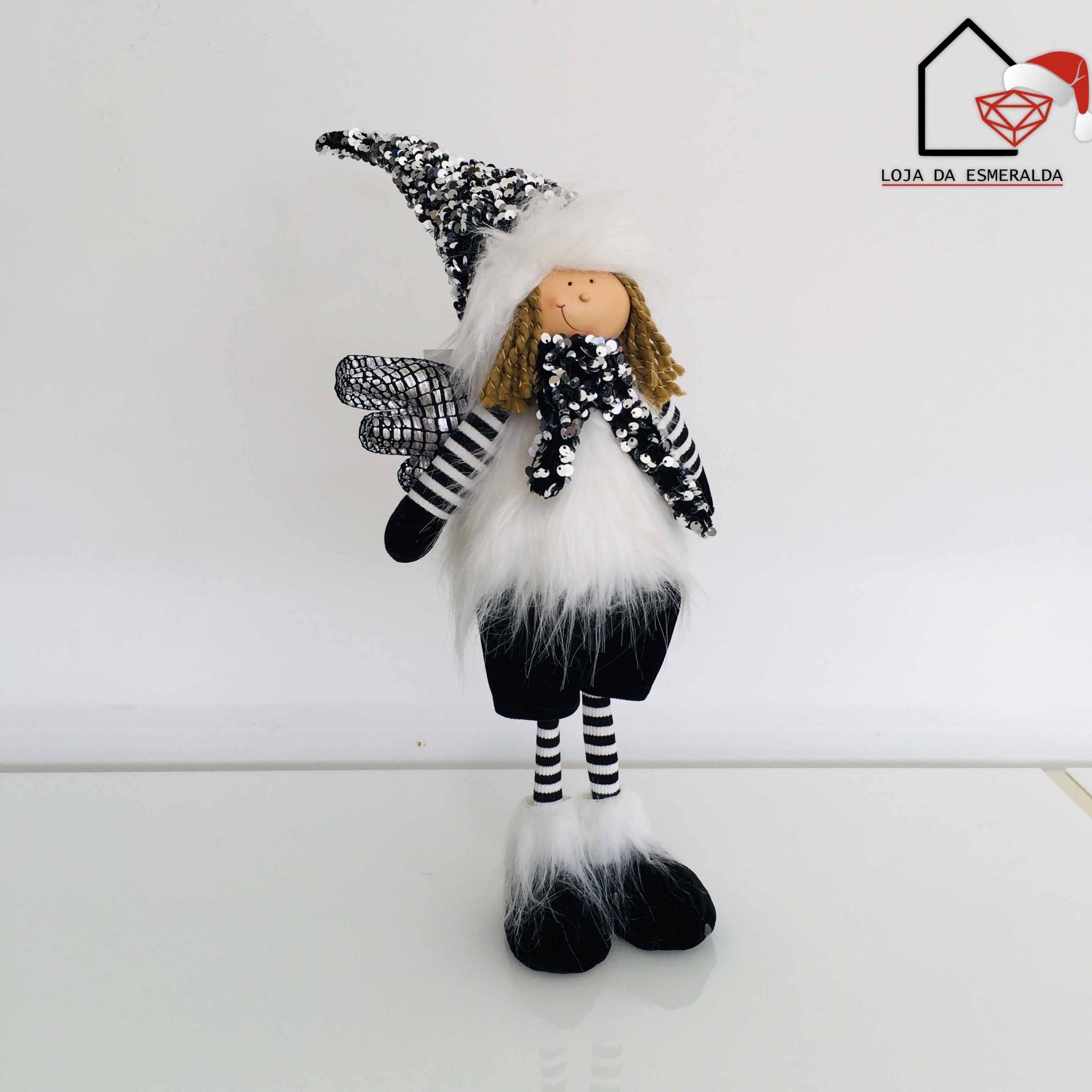 Boneco decorativo preto e branco com chapéu pontiagudo numa superfície branca.