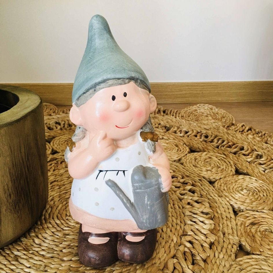 Estátua decorativa de jardim criança com gorro, vestido branco e regador.