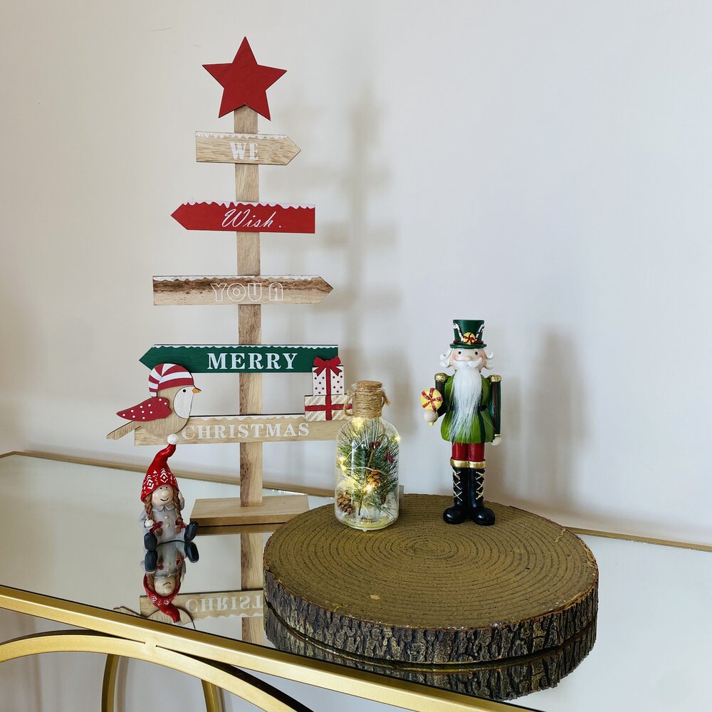 Decoração de Natal com árvore de madeira, figuras natalícias, pote com luzes e soldado quebra-nozes em móvel espelhado