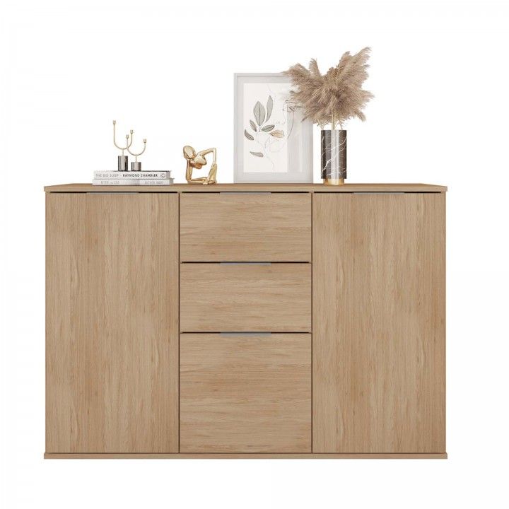 Aparador de madeira clara com gavetas e portas, decorado com livros, candelabro, escultura, moldura e vaso com ramos secos