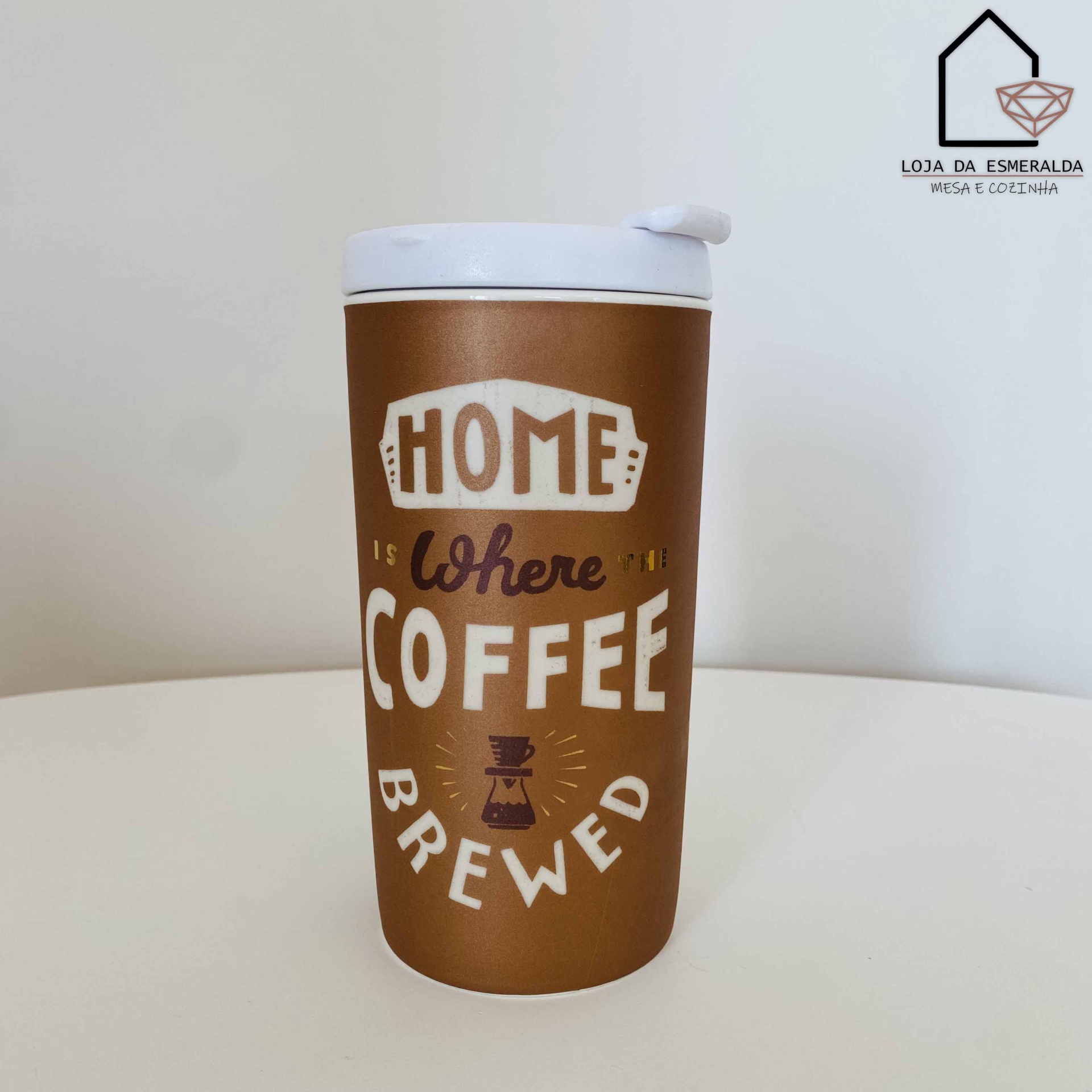 Copo térmico castanho com tampa branca e texto decorativo sobre café