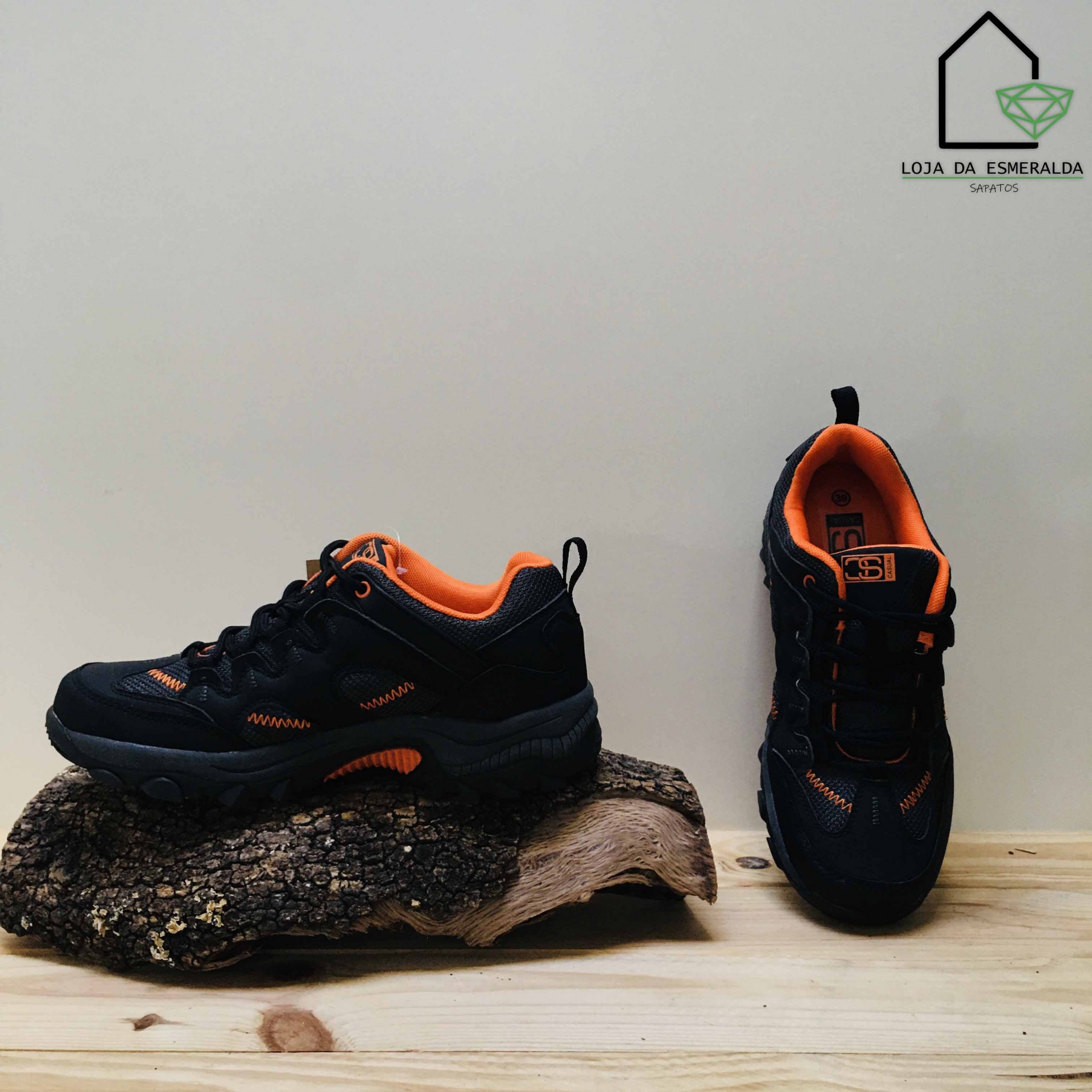 Par de sapatilhas desportivas pretas e laranja sobre madeira.