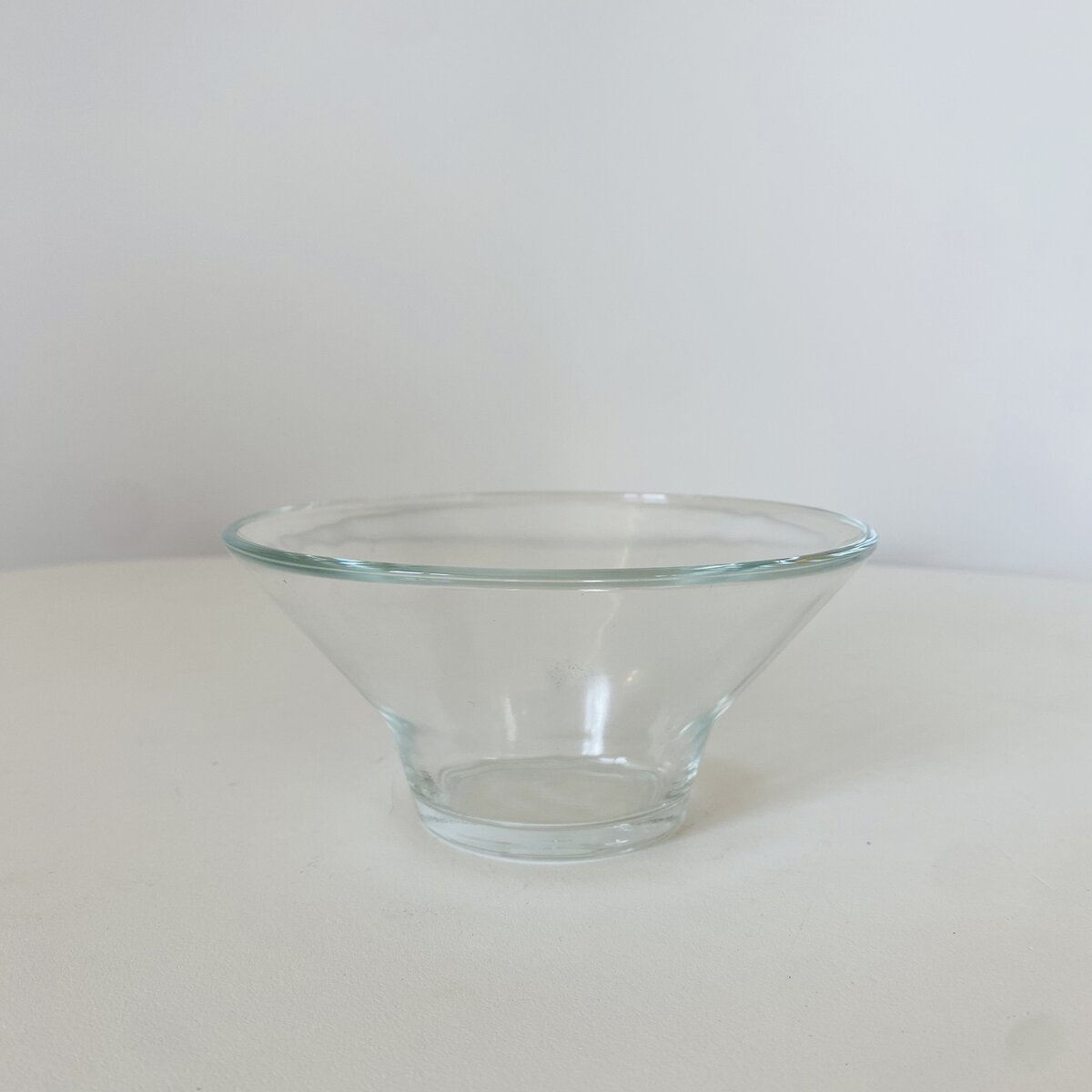 Tigela de vidro transparente cónica numa superfície branca