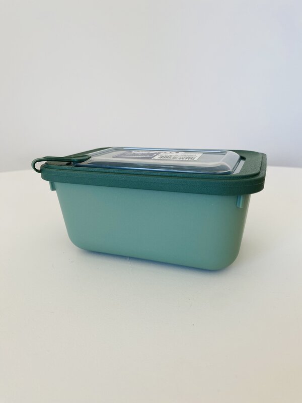 Recipiente de plástico verde com tampa transparente em superfície branca