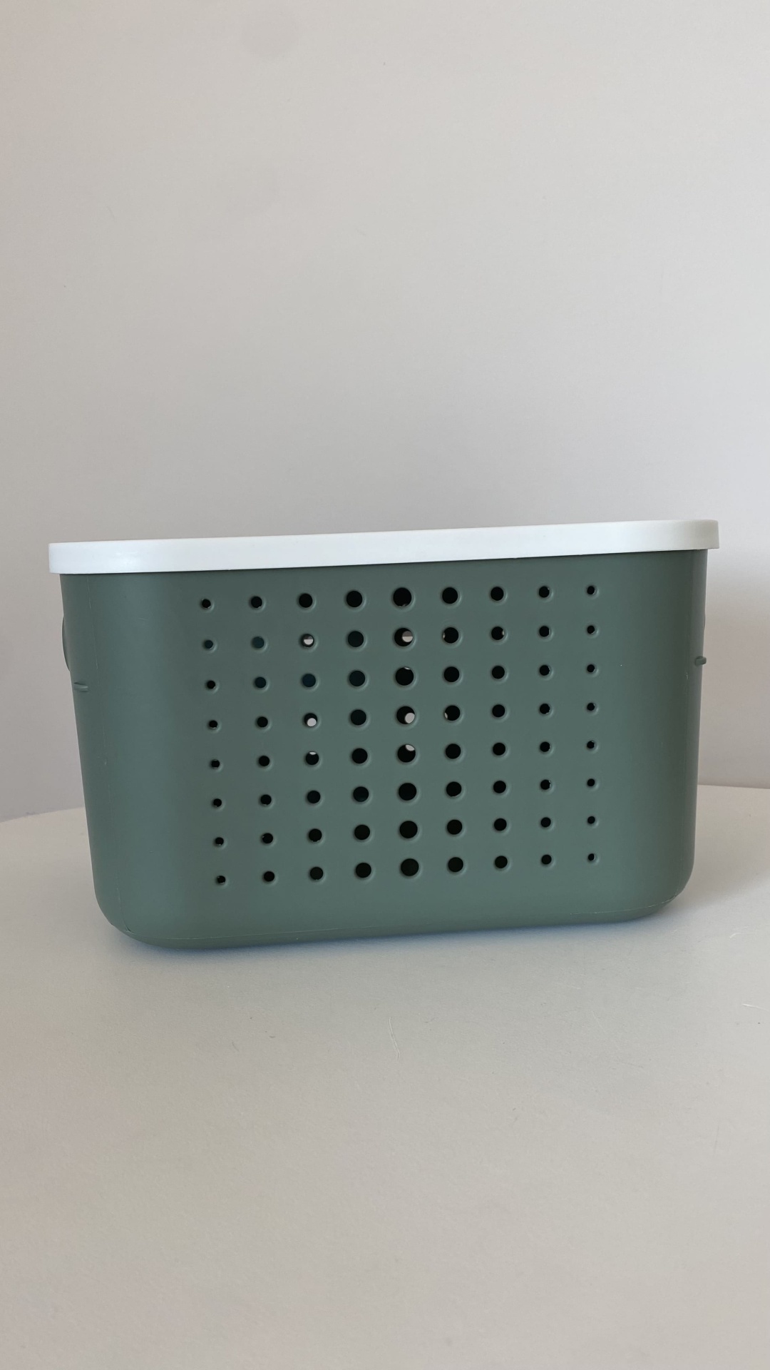 Caixa de plástico verde com tampa branca e furos na lateral