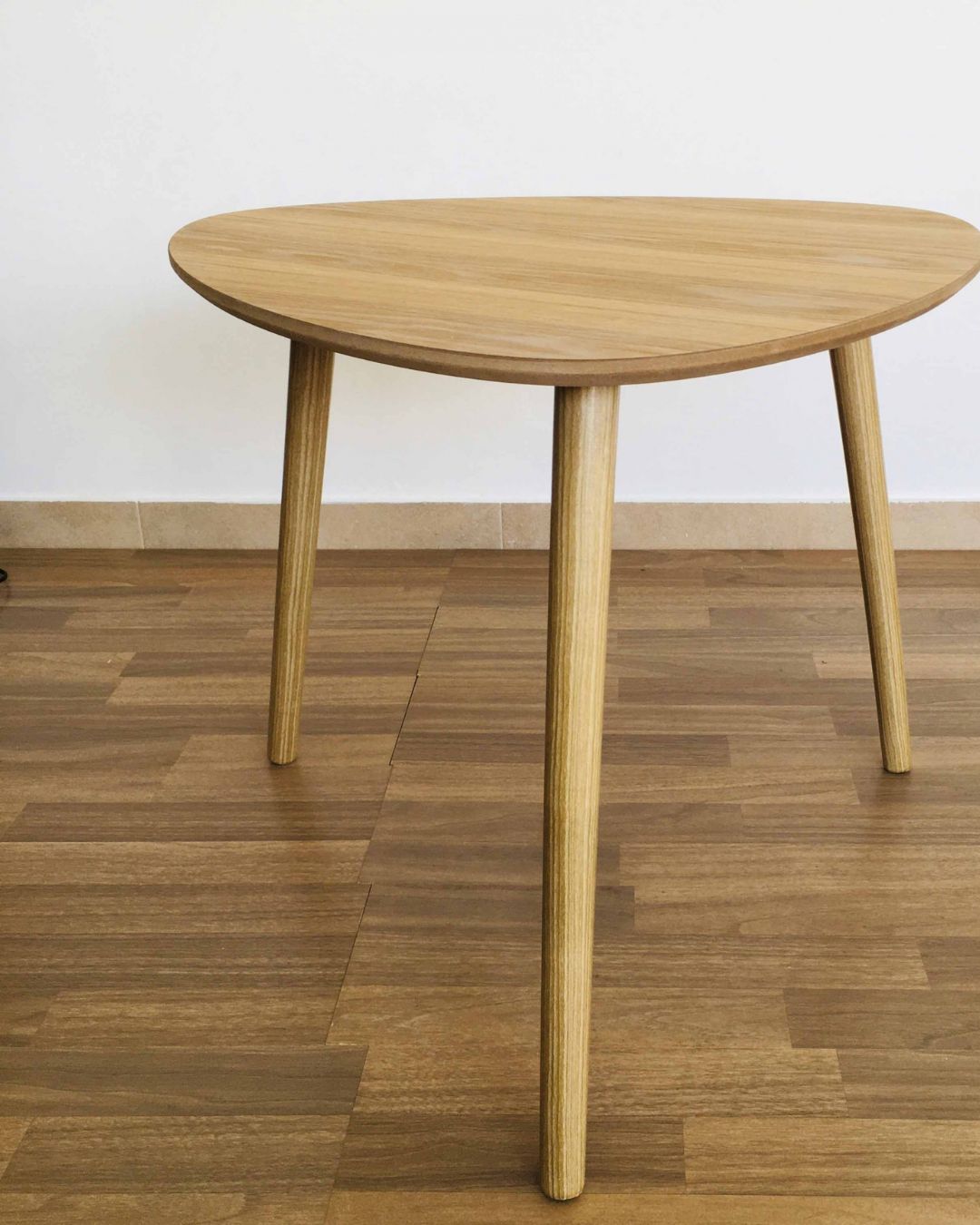 Mesa de madeira clara com tampo triangular e três pernas