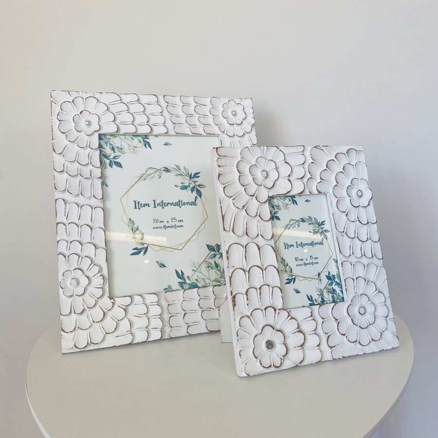 Dois porta-retratos brancos com textura floral e escamada sobre mesa branca