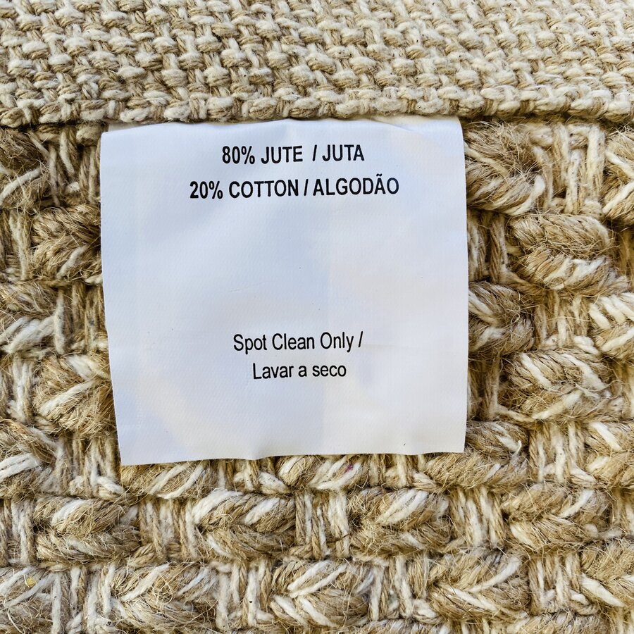 Etiqueta com composição e instruções de limpeza sobre tecido tricotado bege.