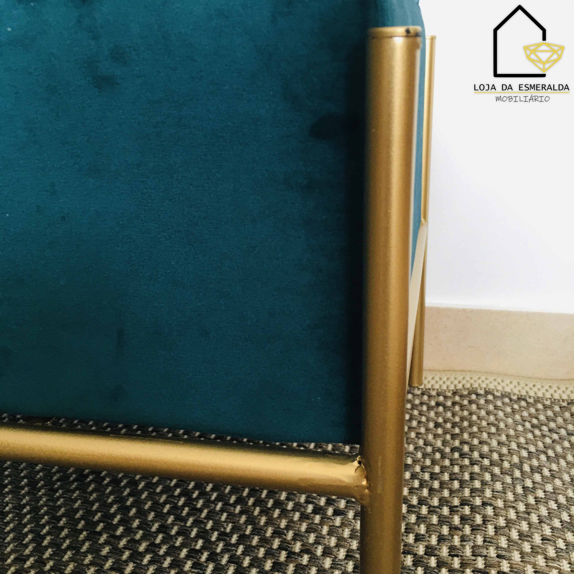 Canto de móvel metal dourado e estofado azul turquesa sobre tapete xadrez castanho e bege